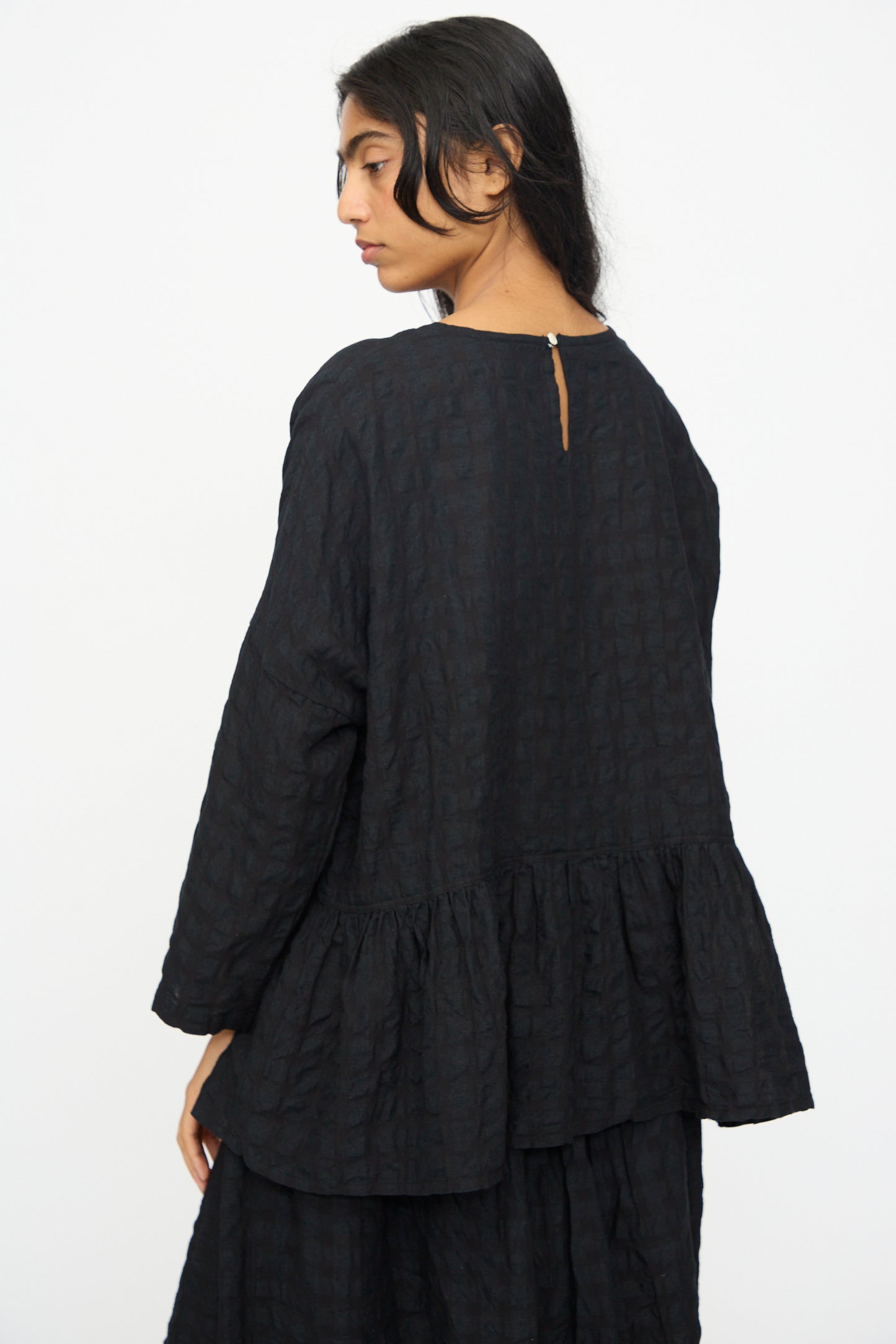 A woman with long dark hair, wearing the Ichi Antiquités Gingham Check Pullover in Black, stands against a plain white background.