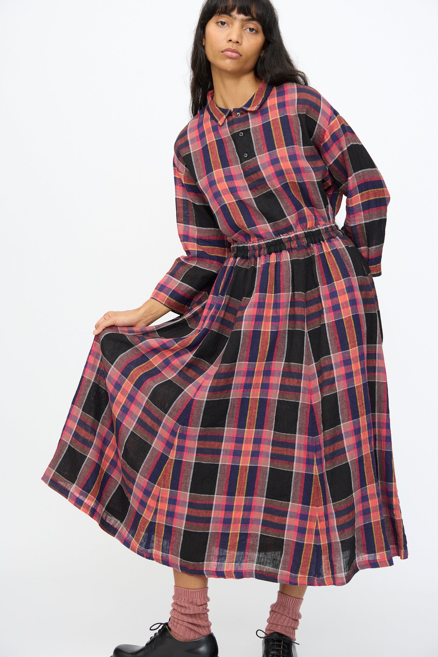 A woman models the Ichi Antiquités Linen Check Skirt in Black, styled with a long-sleeved top and black shoes, against a plain background.