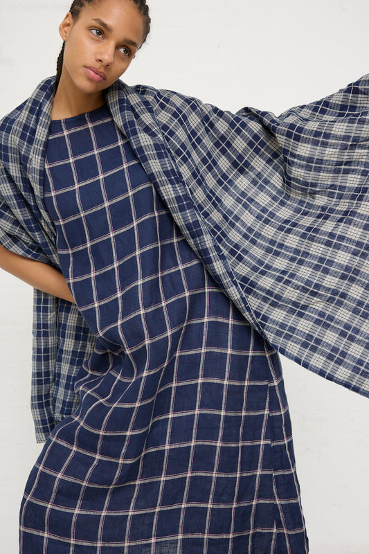 A woman posing in a blue plaid Ichi Antiquités dress with a flowing sleeve design, complemented by an Ichi Antiquités Linen Check Stole in Dark Indigo and Natural.
