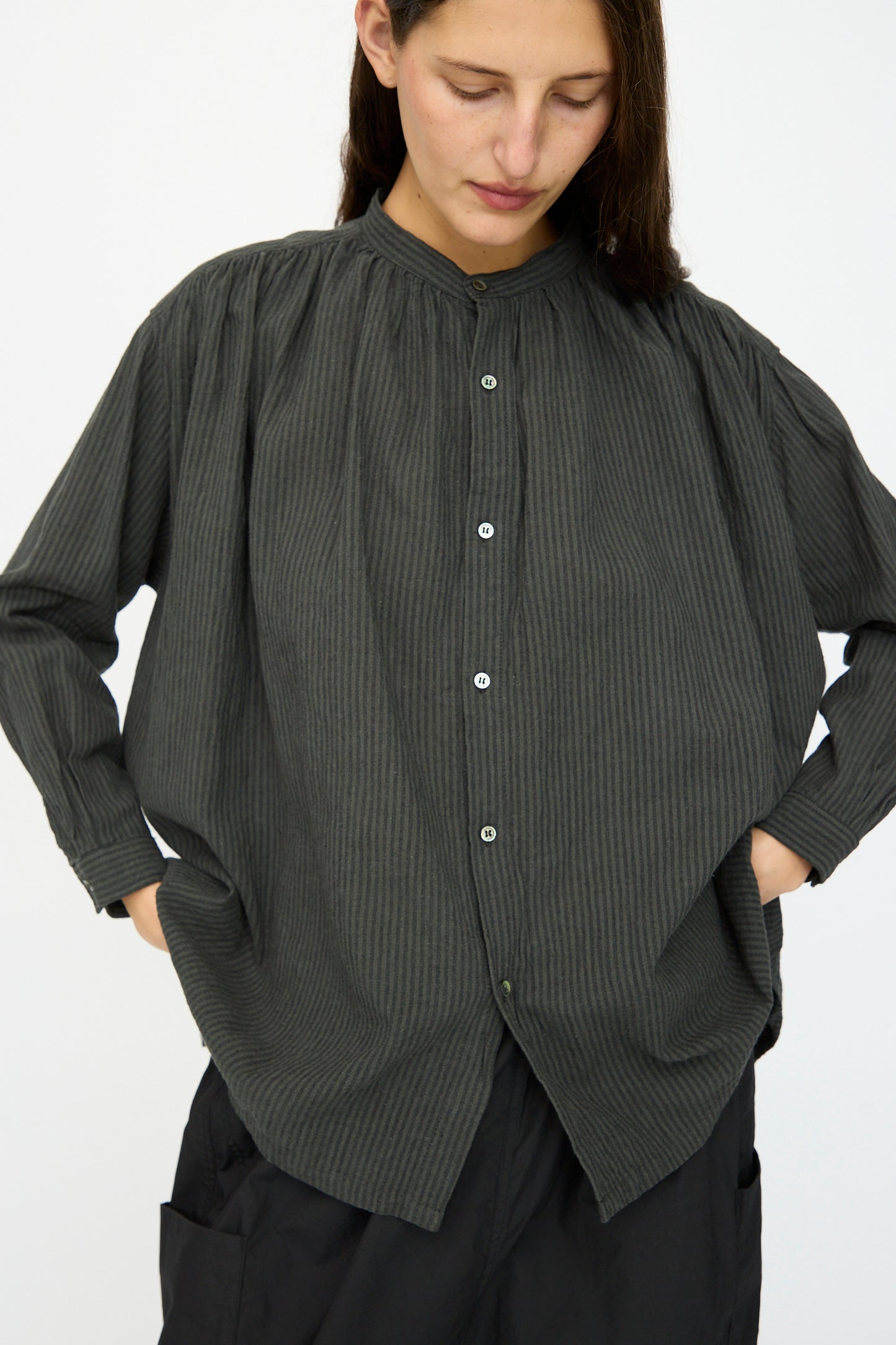 A person models the Ichi Antiquités Linen and Cotton Stripe Shirt in Charcoal, hands in pockets, standing against a plain white background.