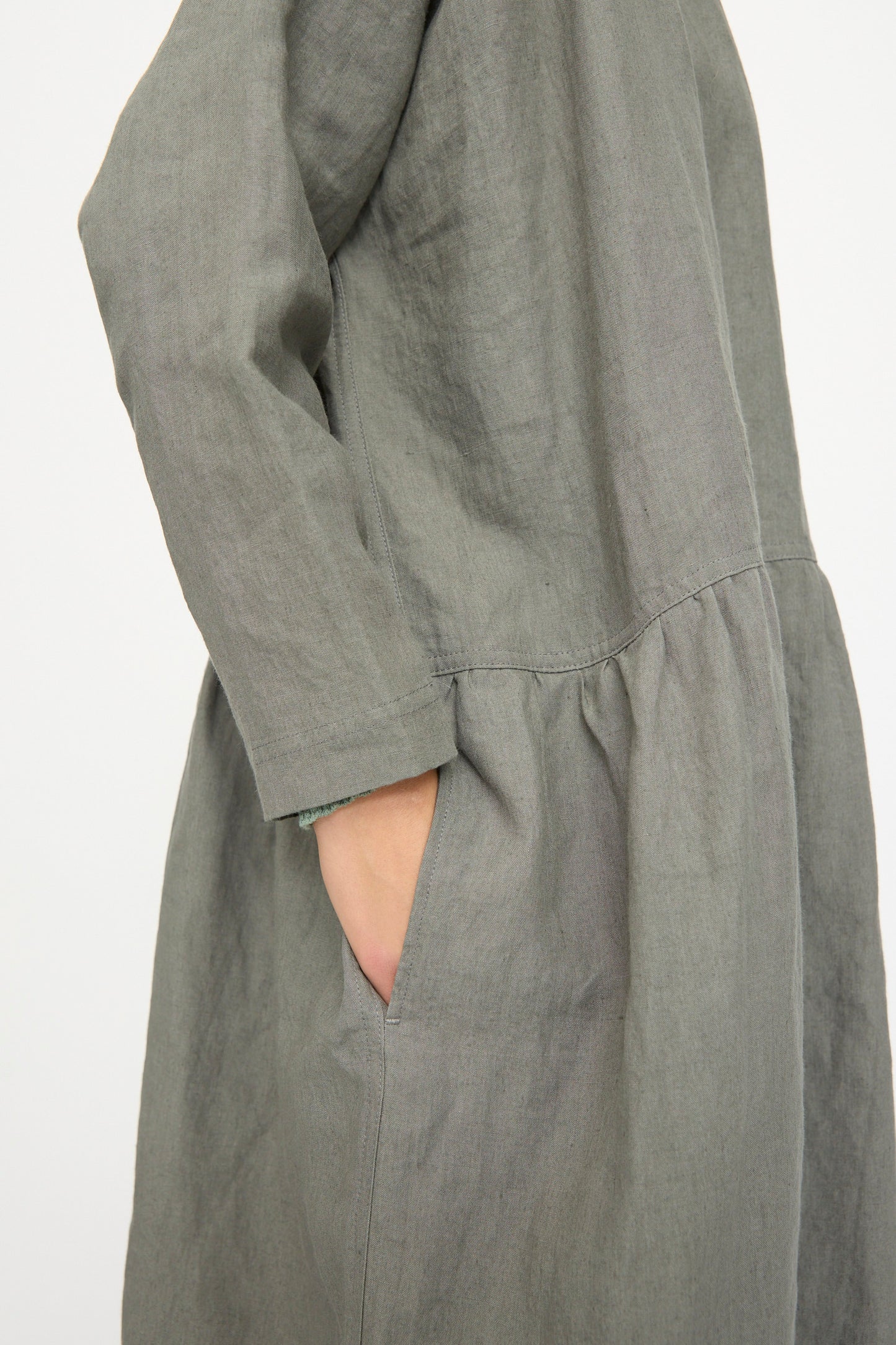 A person wearing the Ichi Antiquités Linen Dress in khaki, featuring a loose fit, long sleeves, and side pockets; made in Japan.