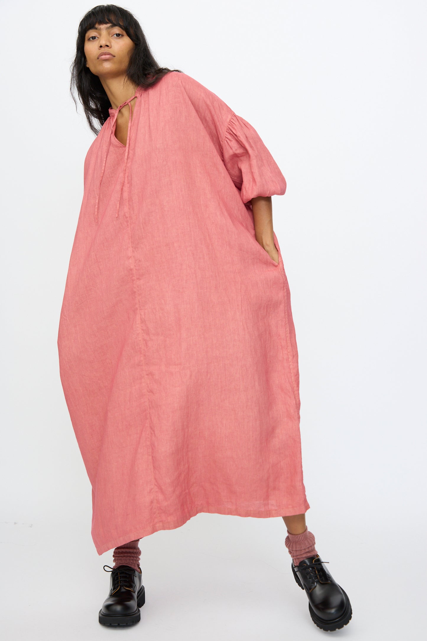 A person wears the Ichi Antiquités Linen Dress in Pink, styled with pink socks and black shoes, standing against a plain white background.