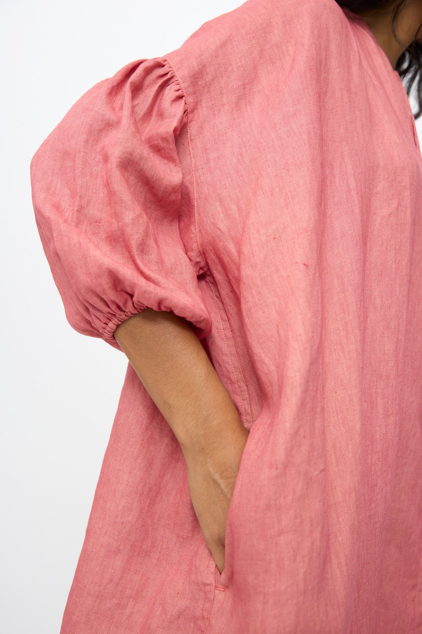 Close-up of a person wearing the Ichi Antiquités Linen Dress in Pink, featuring an oversized fit, puffed sleeves, and one hand tucked into a pocket.