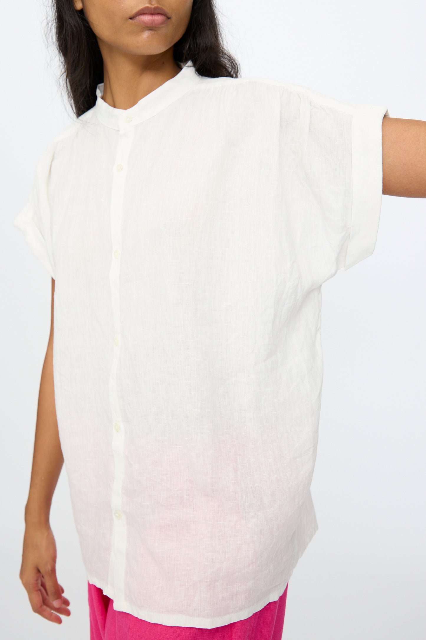 A person wears the Ichi Antiquités Linen Dungaree Blouse in White, a loose-fitting, short-sleeved oversized top, paired with bright pink pants against a plain background.