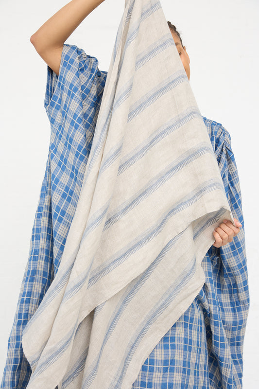 A person in an Ichi Antiquités Linen Stripe Stole in Natural and Indigo lifting a striped linen stole against a white background.