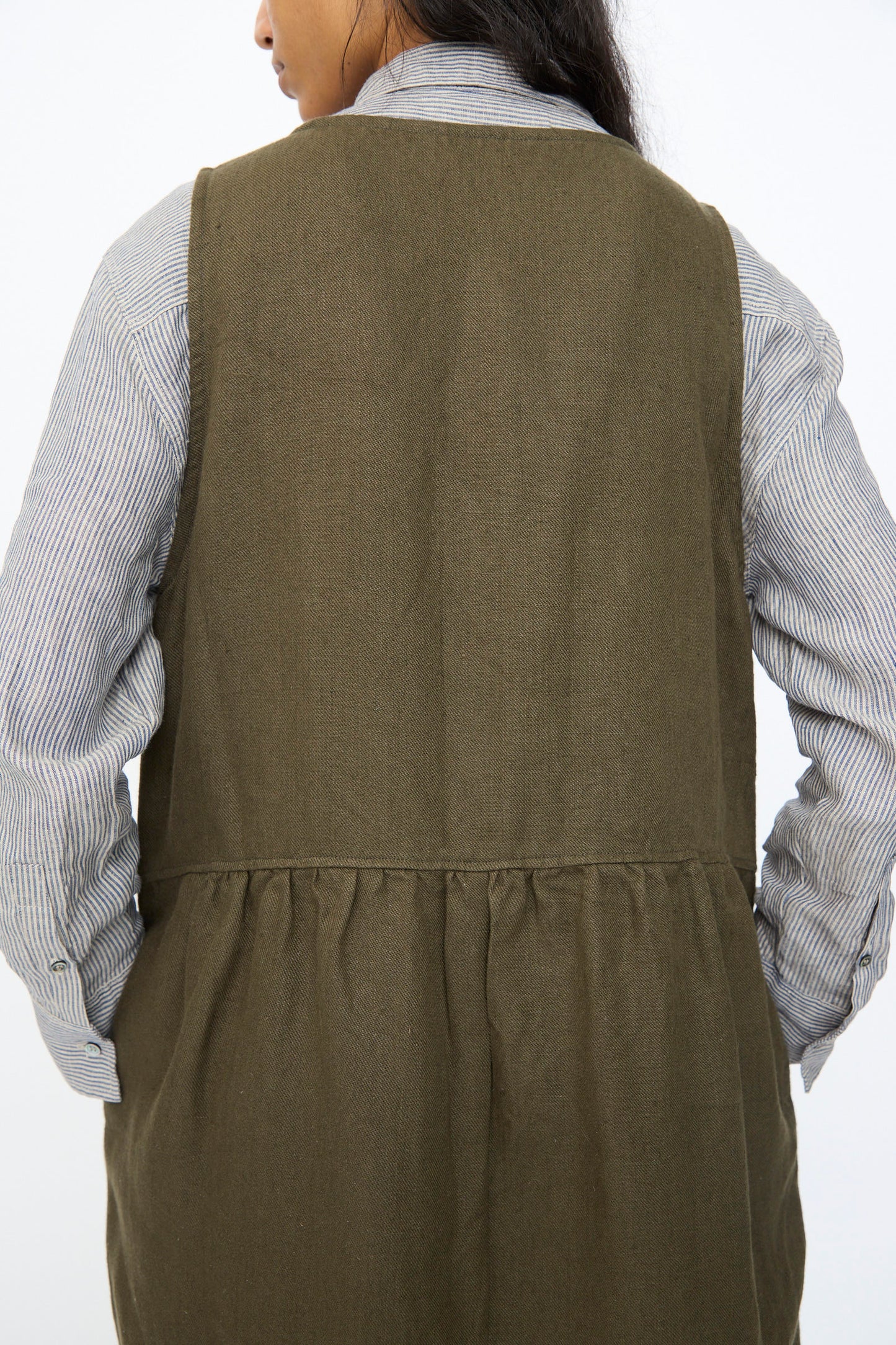 A person shown from the back against a plain background wears the Ichi Antiquités Twill Weave Linen Jumpsuit in Khaki over a gray striped long-sleeve shirt.