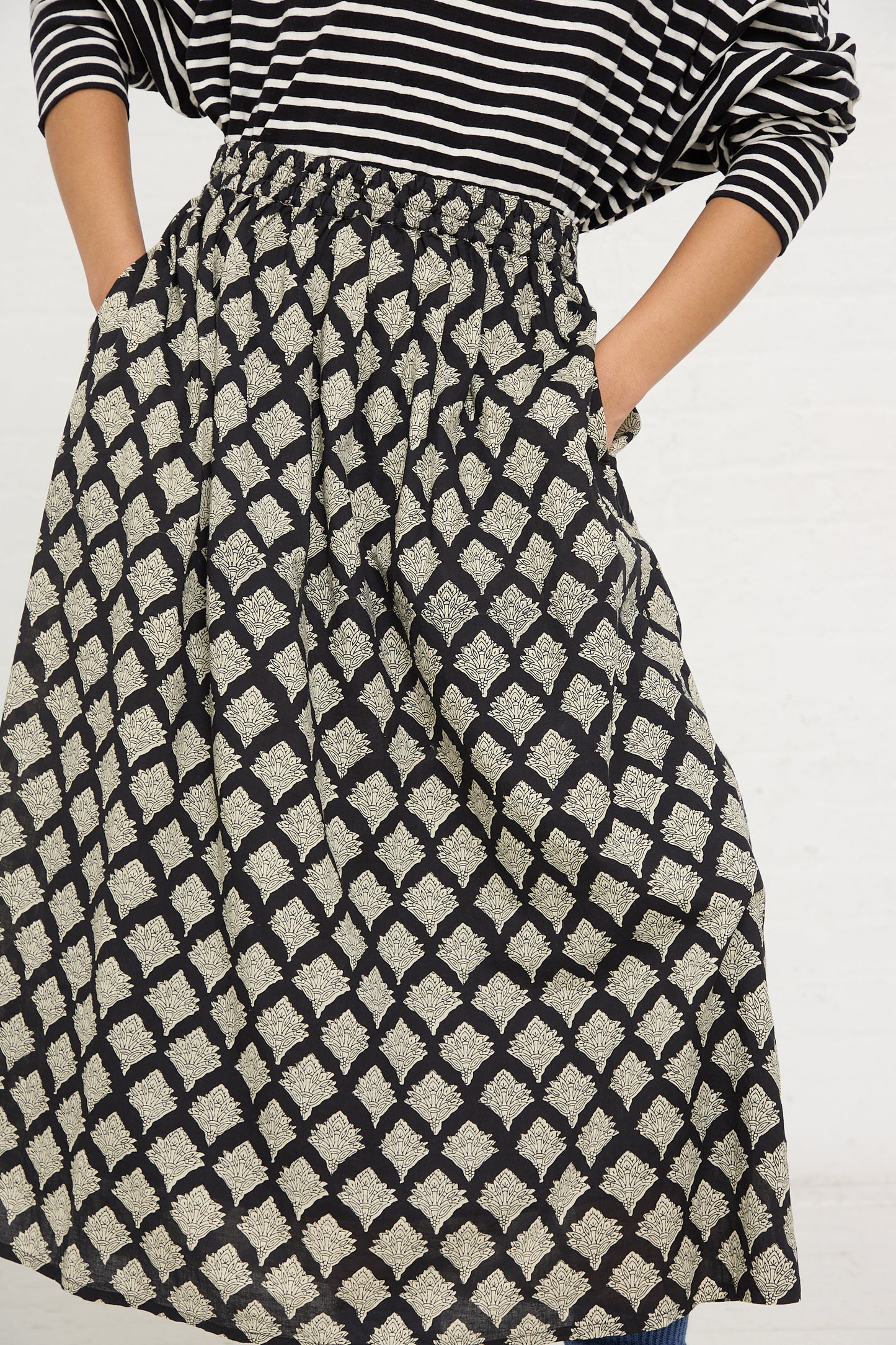 A person wearing a black and white Ichi Antiquités woven cotton Indian block print midi skirt with pockets, paired with a striped top.