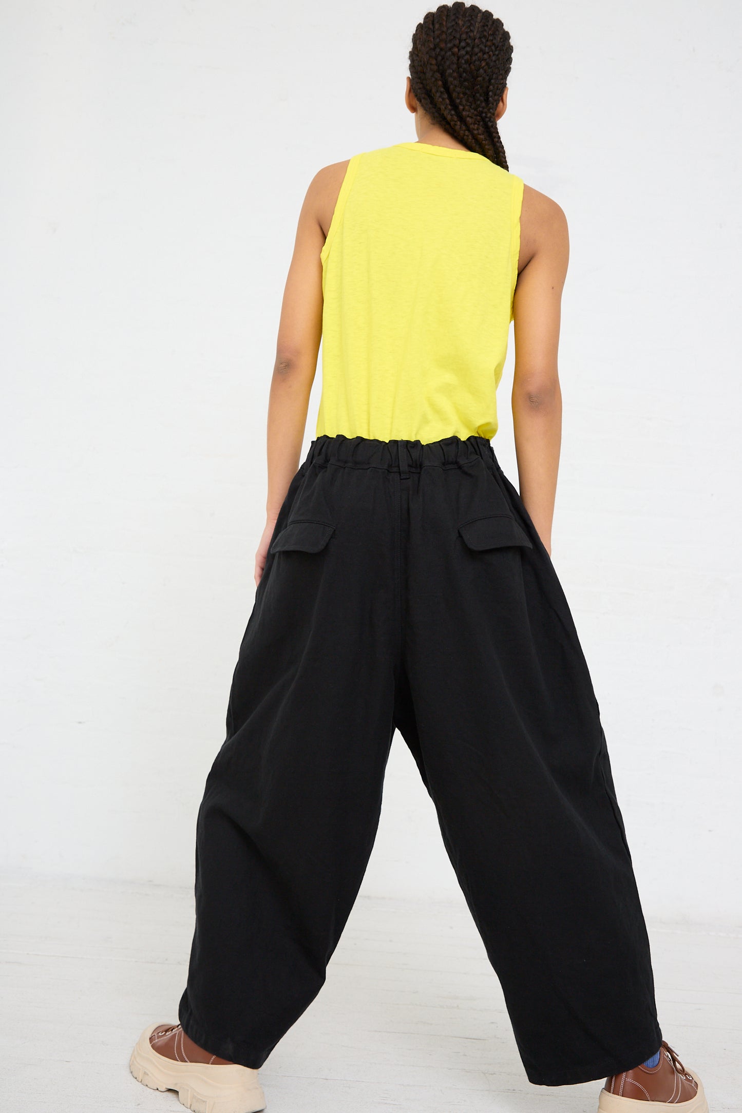 Woman standing with her back to the camera, wearing a yellow tank top and baggy Ichi Antiquités Woven Cotton Linen Pant in Black.