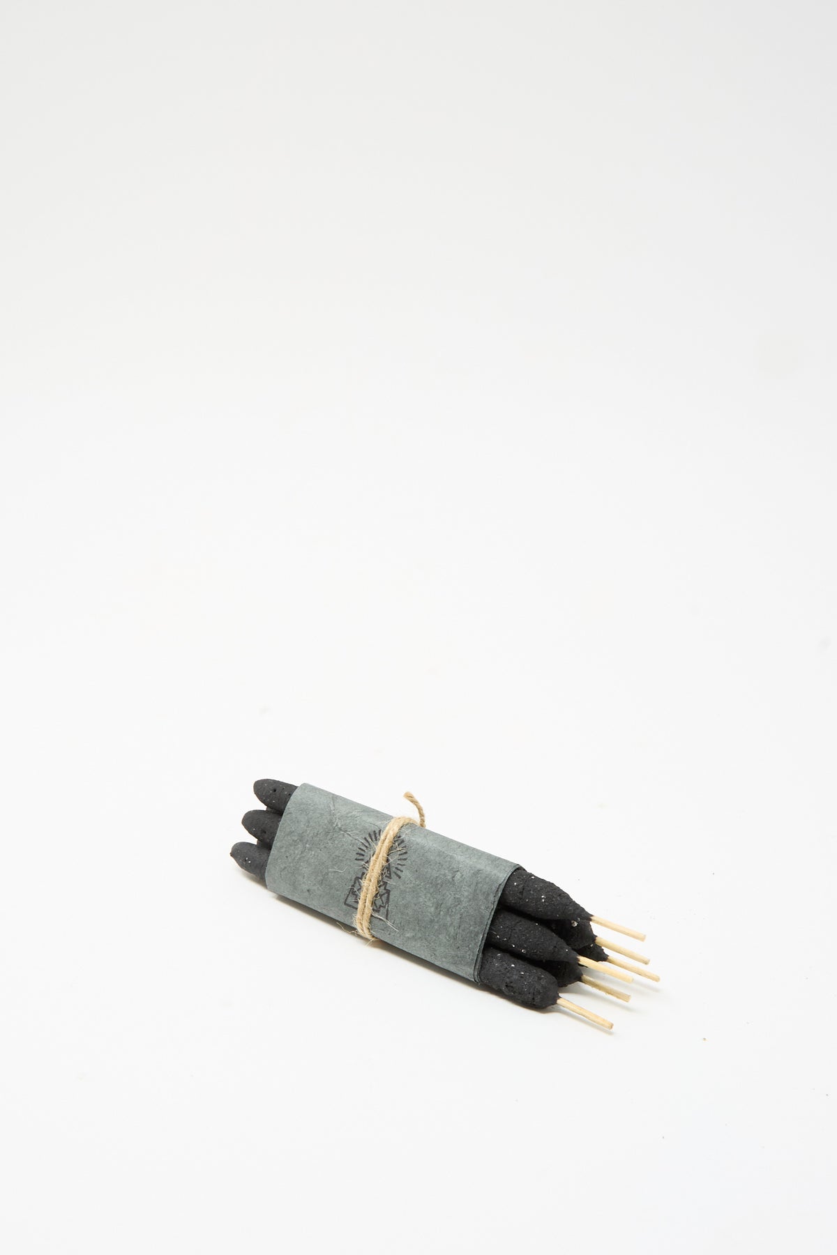 Six dark artisanal Half Dozen Incense Bundles in White Sage wrapped in gray paper and tied with twine.