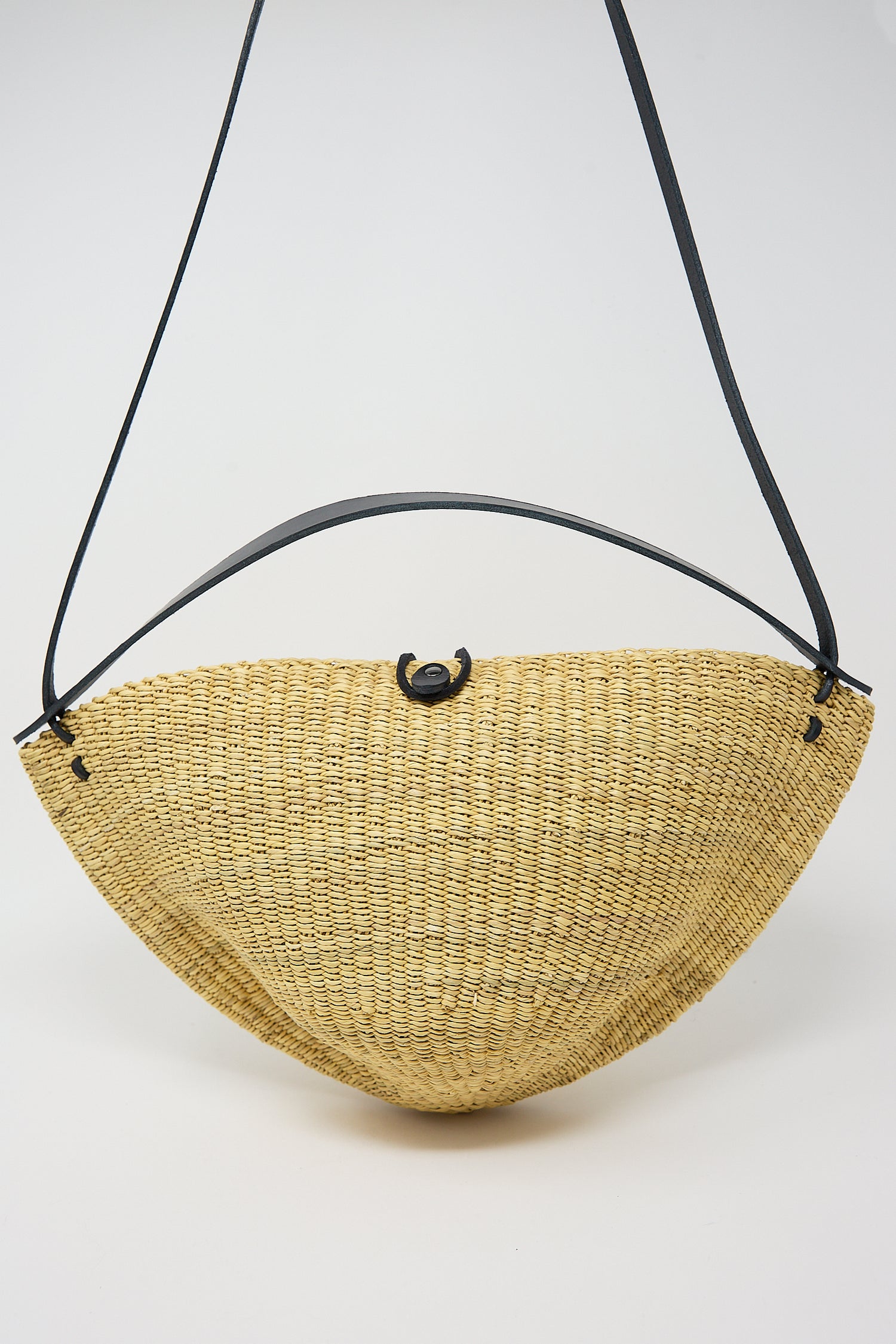 Woven yellow half-moon shaped N. 33 Medium Walnut Bag in Natural made from elephant grass with a black strap by Inès Bressand.