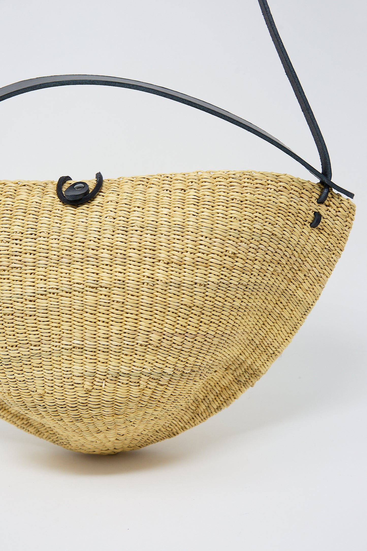 Woven yellow half-moon shaped handbag made from elephant grass with a black strap. 
Product Name: N. 33 Medium Walnut Bag in Natural 
Brand Name: Inès Bressand