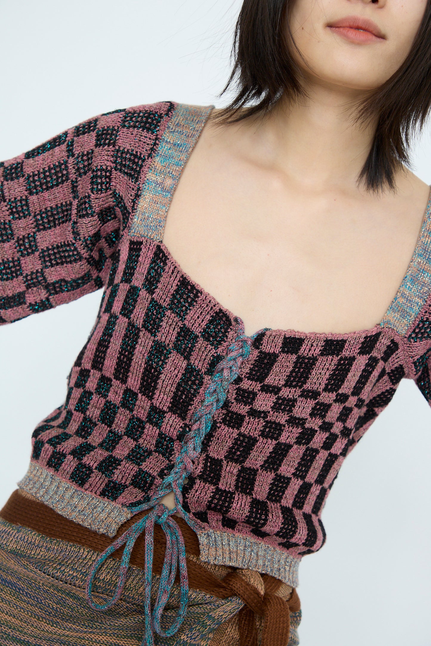 A person wears Intensity’s Wing Corset in Pink, paired with a brown skirt featuring a tied waist against a plain background.