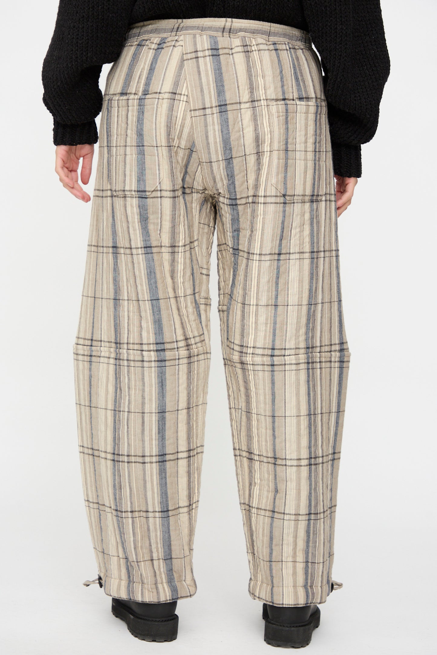 Person wearing Jan-Jan Van Essche Madras Plaid Trouser #89 in Plaster, featuring a relaxed fit and drawstring hems, paired with black shoes. Photographed from the back against a plain background.