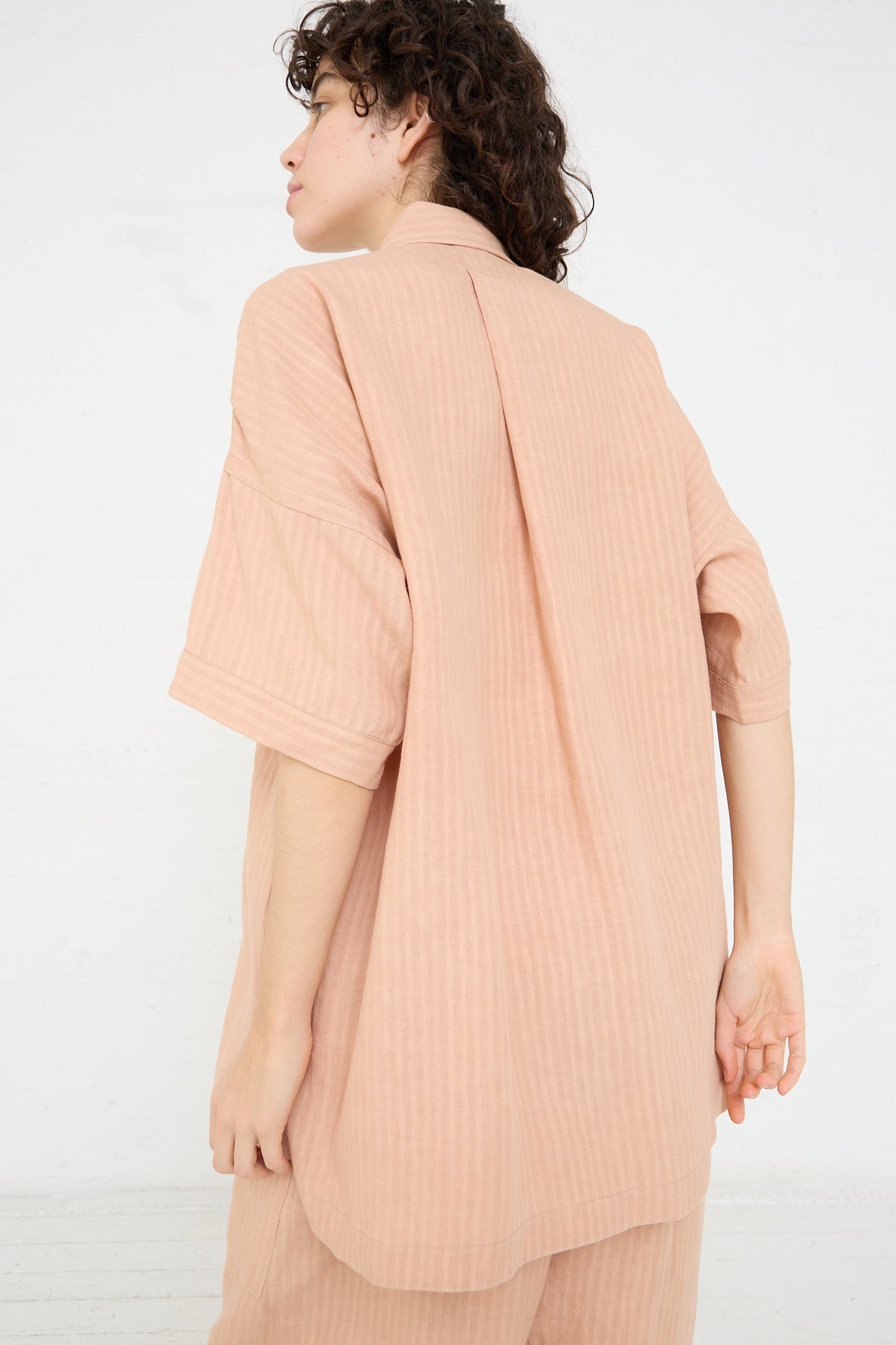 The back view of a woman in a relaxed-fit Jan-Jan Van Essche Ume (Pink) Woven Linen Shirt.