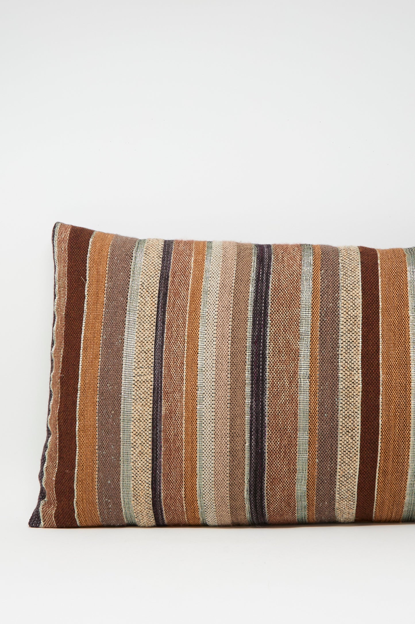 The Jess Feury Woven Pillow in Rust and Terracotta Stripe features a rectangular handwoven design with vertical stripes in earthy tones, crafted from sustainable fibers and displayed against a plain white background.