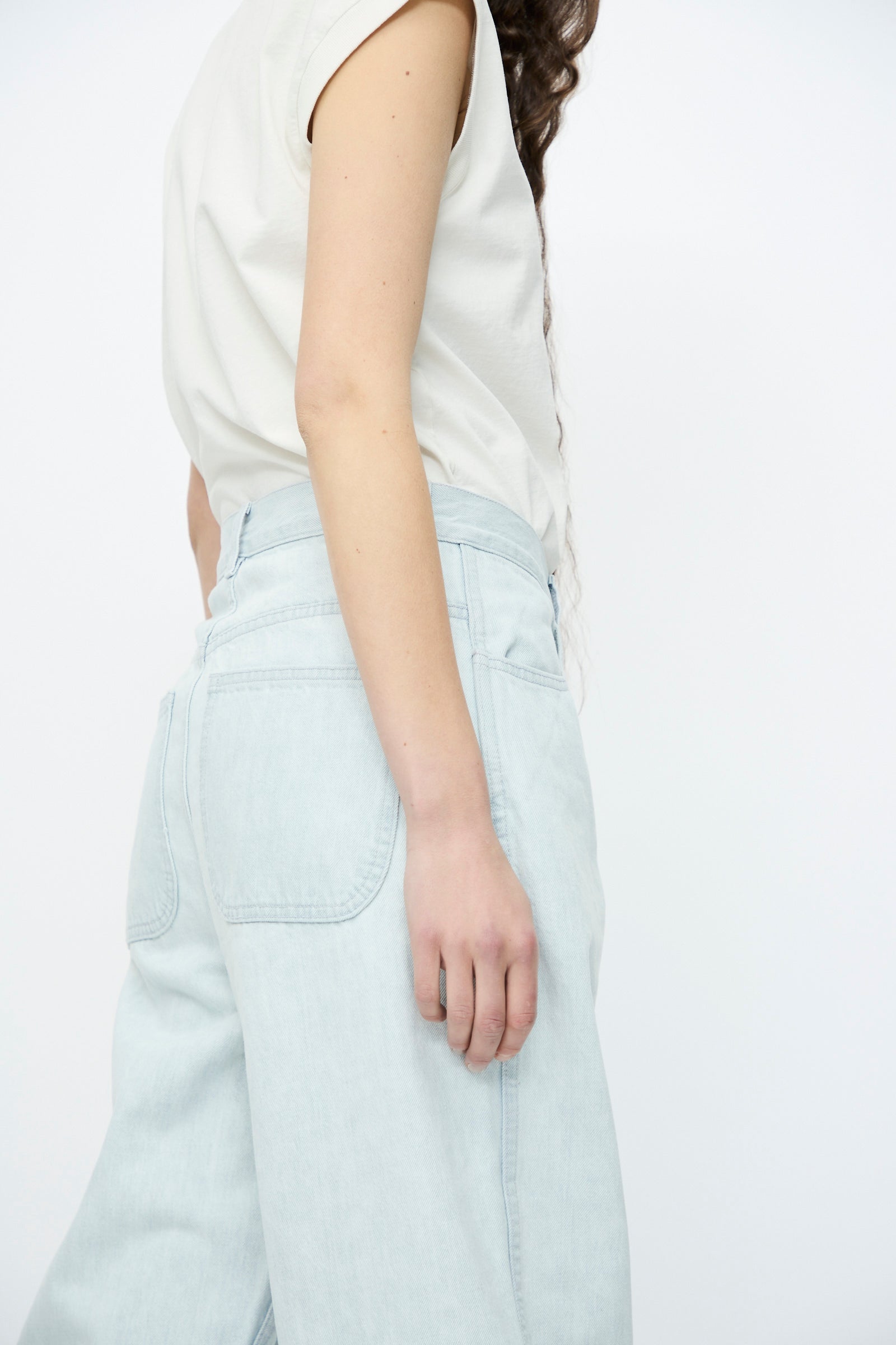 A person stands against a plain white background, wearing Jesse Kamm's Japanese Denim California Wide in Pale Blue paired with a classic white t-shirt.