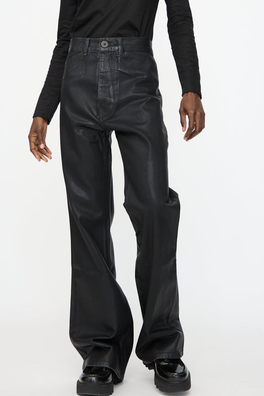 A person wearing Jesse Kamm Japanese Denim Les Deux Pants in Black Lacquer with a long-sleeve black shirt, standing against a plain white background.