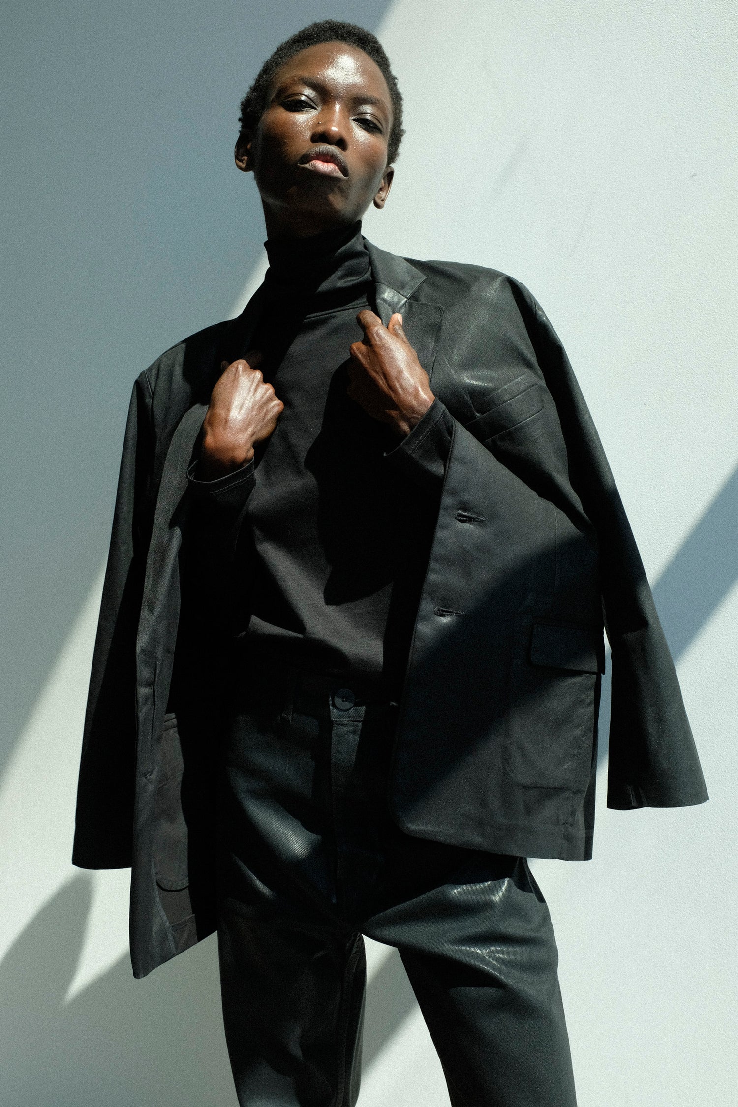 Person wearing a black suit against a white background.