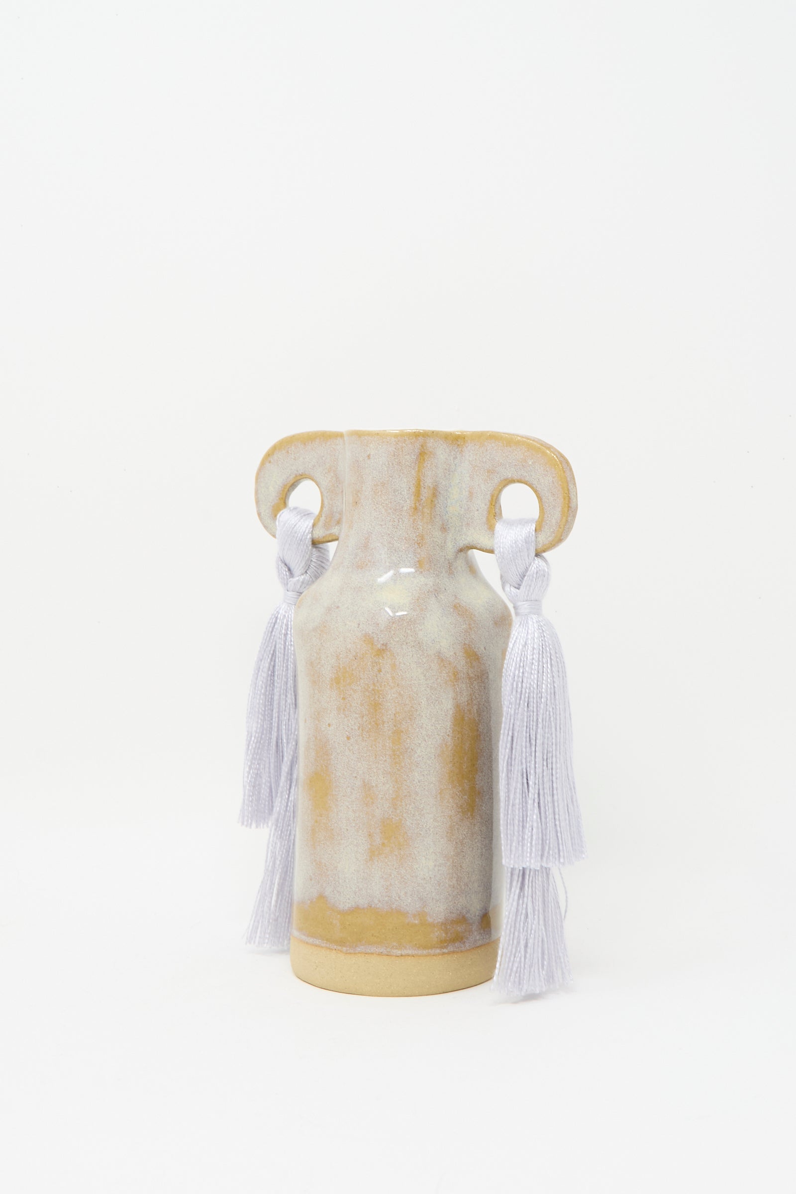 The Karen Tinney Vase #606 in Gray is a petite stoneware vase with two handles, handmade in Vermont, featuring white tassels on each handle and a light brown and white glaze, shown against a plain white background.