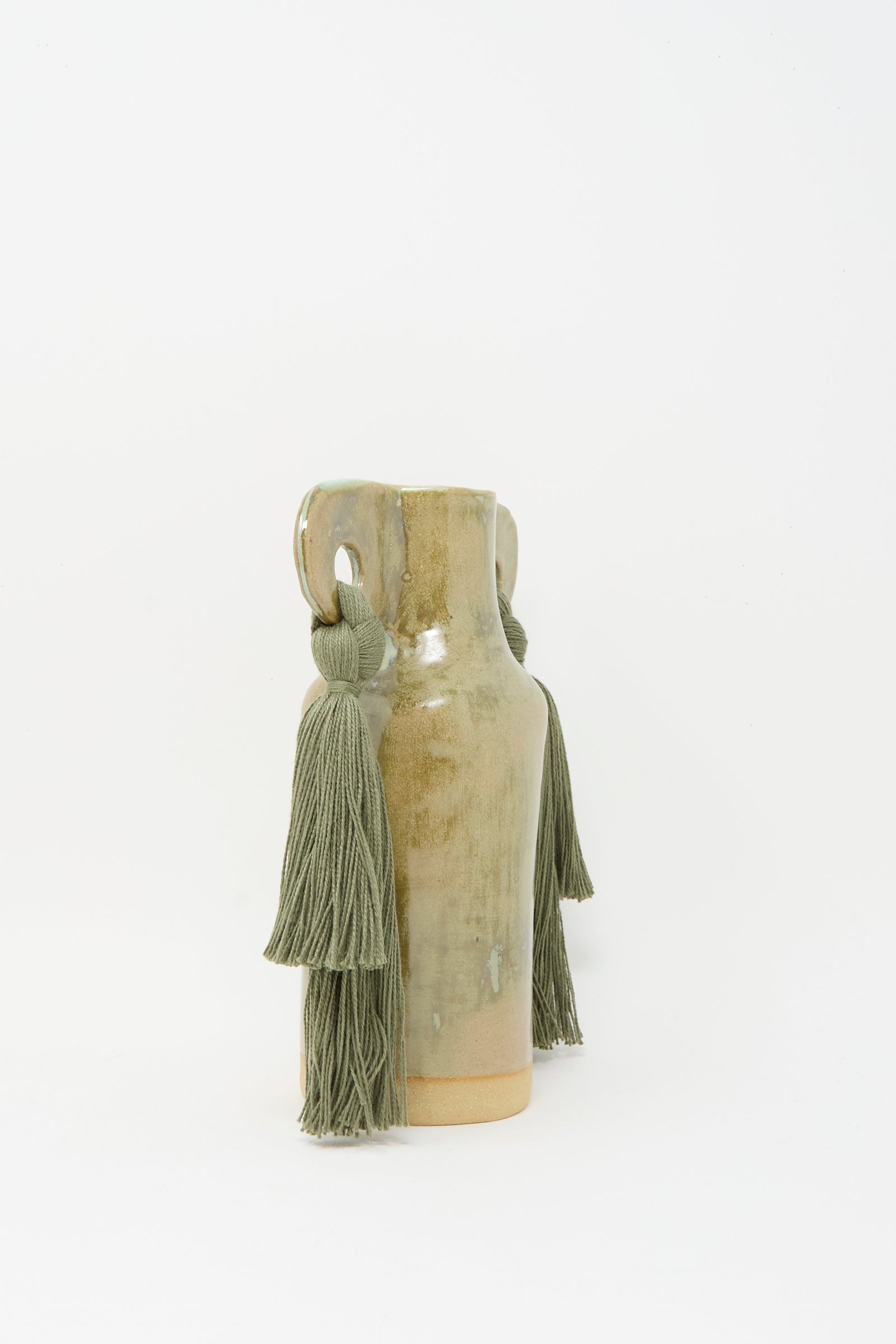 The Karen Tinney Vase #606 in Olive is a petite handmade stoneware vase with a glossy olive glaze and two handles accented by thick green tassels, shown on a plain white background.