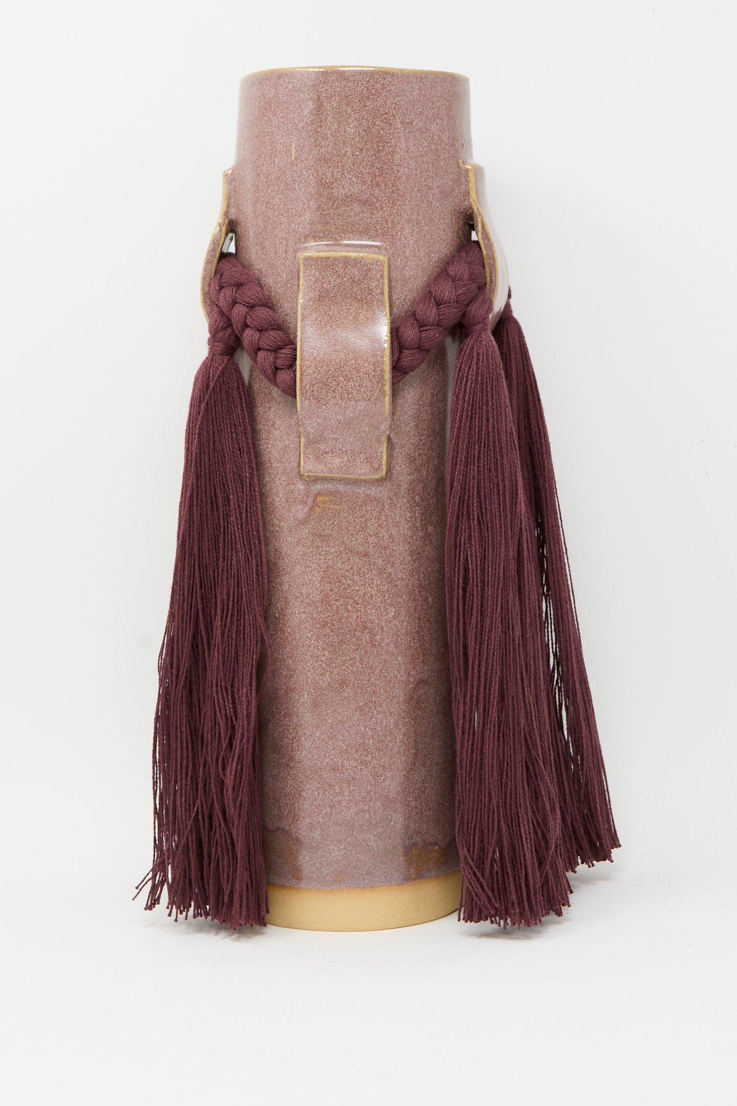 The Karen Tinney Vase #800 in Burgundy is a tall, cylindrical stoneware piece featuring a gold rectangular accent and two thick braided tassels, inspired by classic Vermont pottery.