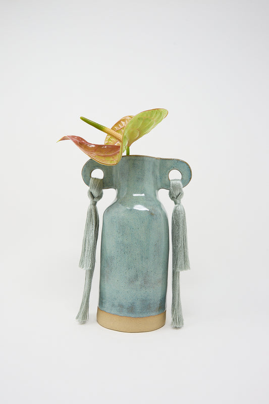 Handmade ceramic Vase #606 in Sage with tassel handles and a pair of tropical leaves by Karen Tinney.