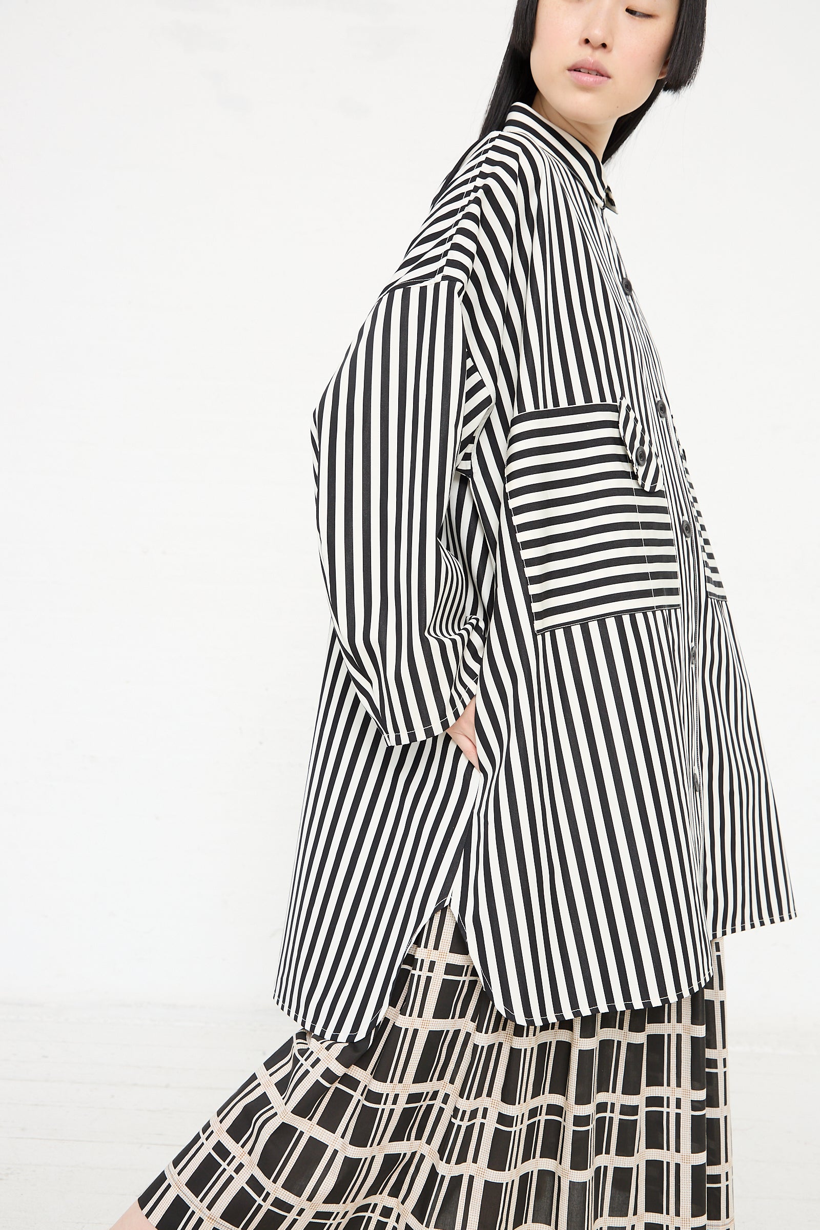 A person wearing a KasMaria Cotton Poplin Oversized Smock Dress in Stripe with black and white stripes and a relaxed fit, showcasing a modern design against a white background.