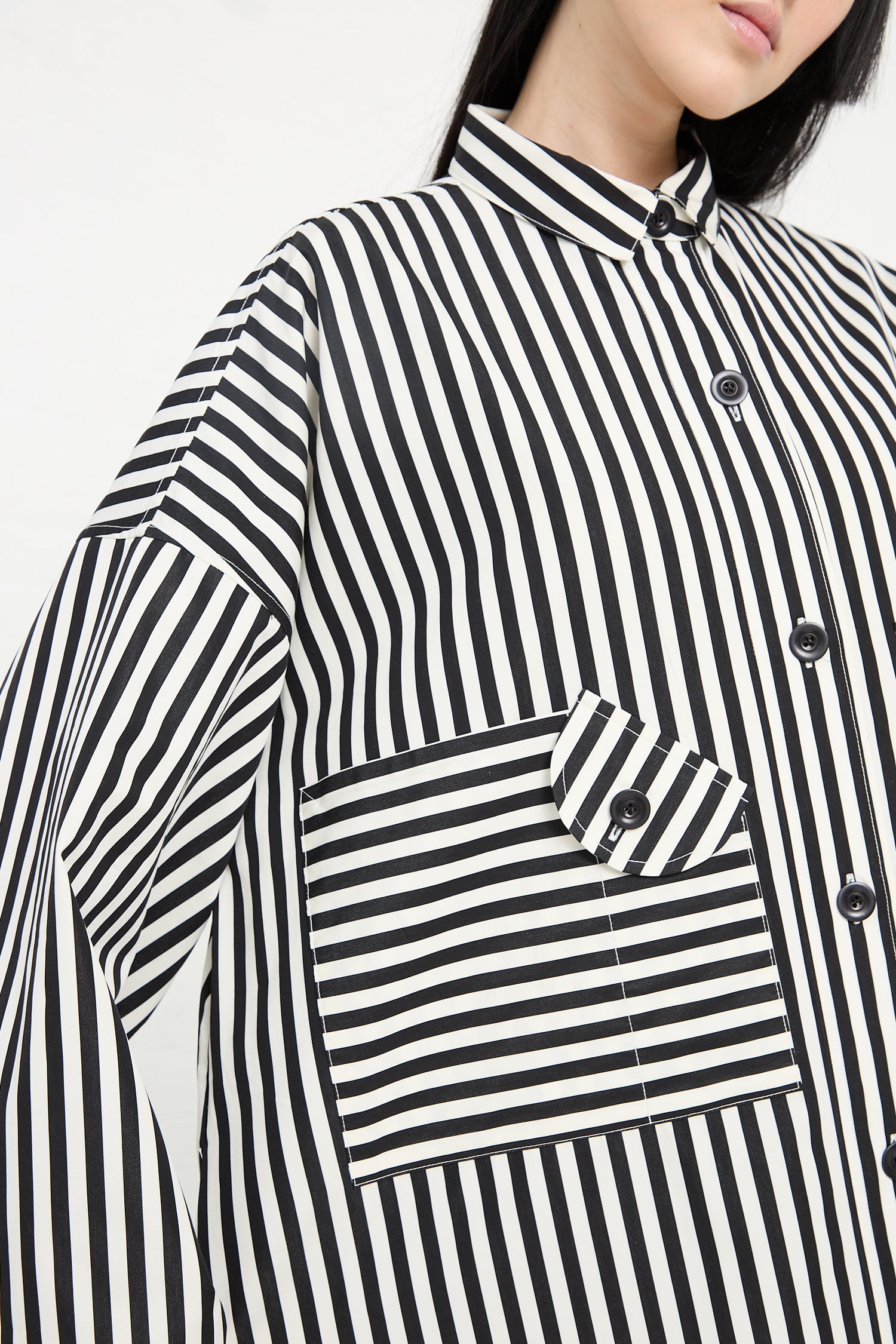 A close-up of a person wearing a KasMaria Cotton Poplin Oversized Smock Dress in Stripe with a focus on the pocket detail.
