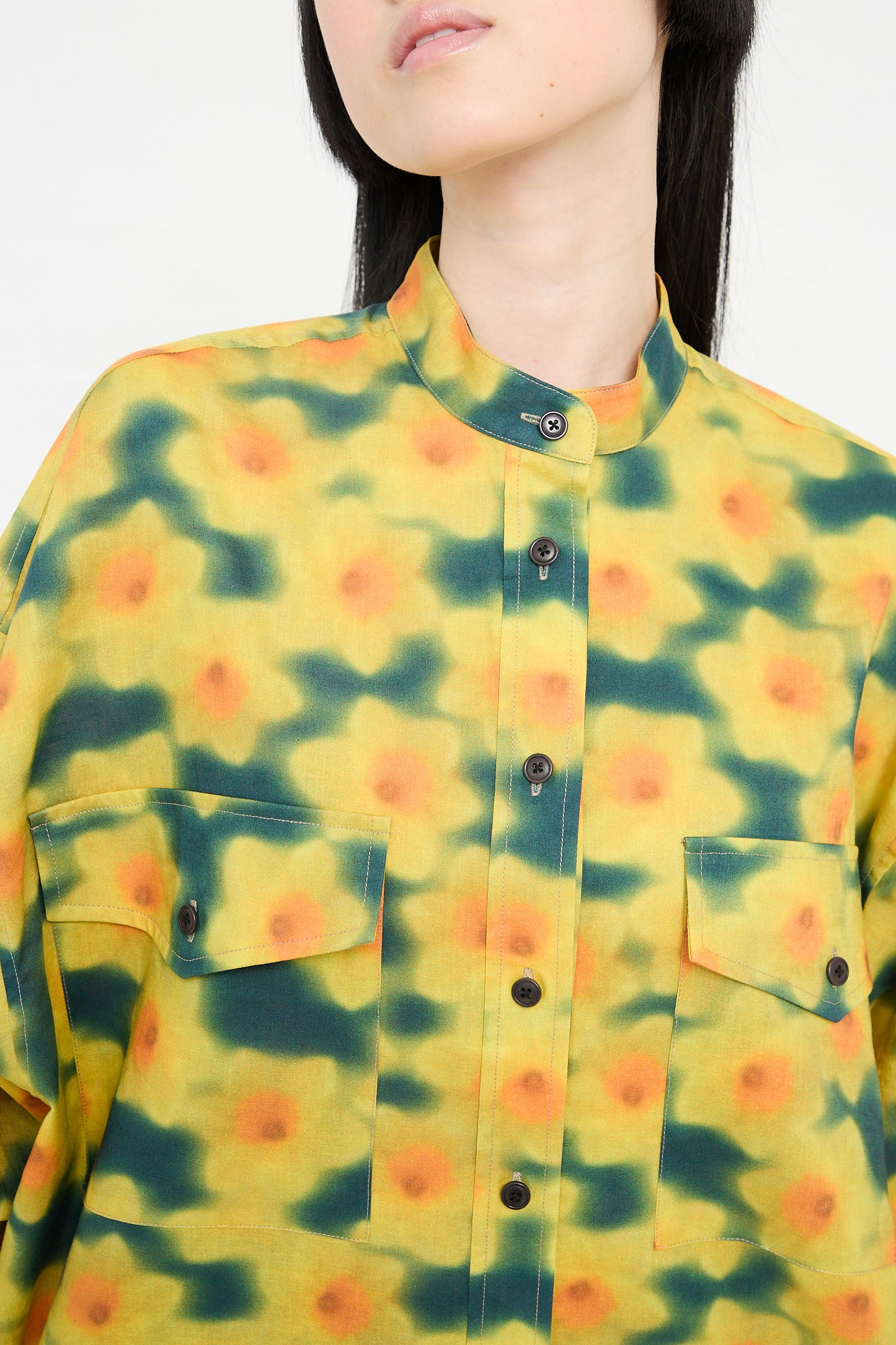 Woman wearing a KasMaria Cotton Linen Large Front Pocket Shirt in Daffodil Print, featuring a collarless design and button-up closure.