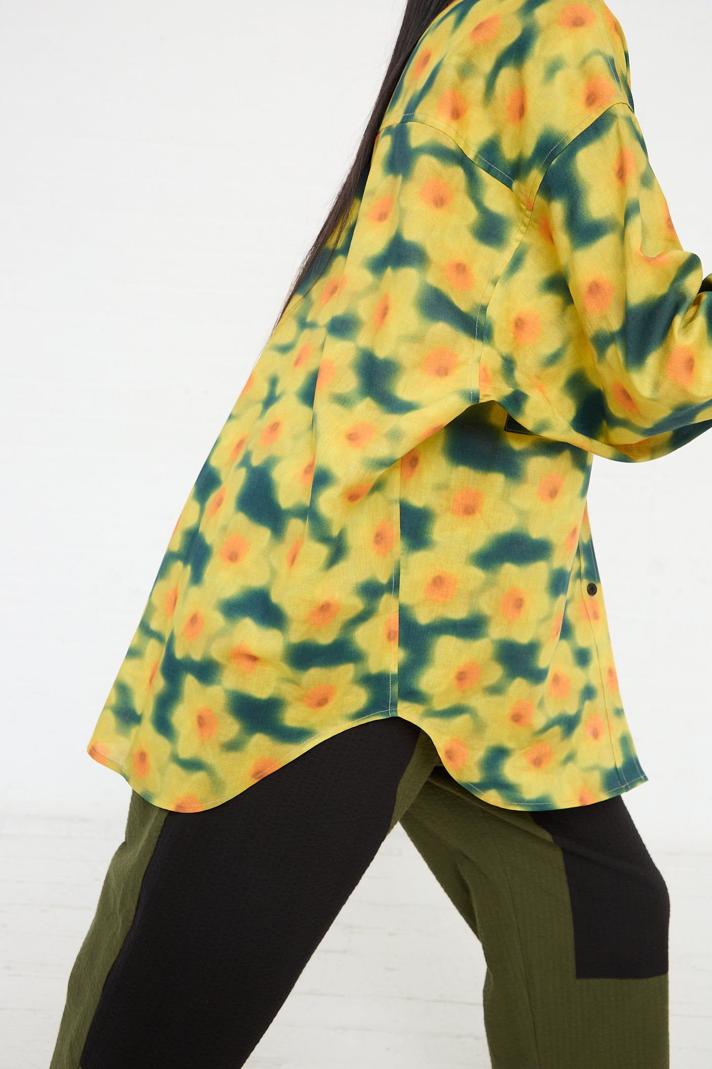 A person wearing a KasMaria Cotton Linen Large Front Pocket Shirt in Daffodil Print paired with olive pants.