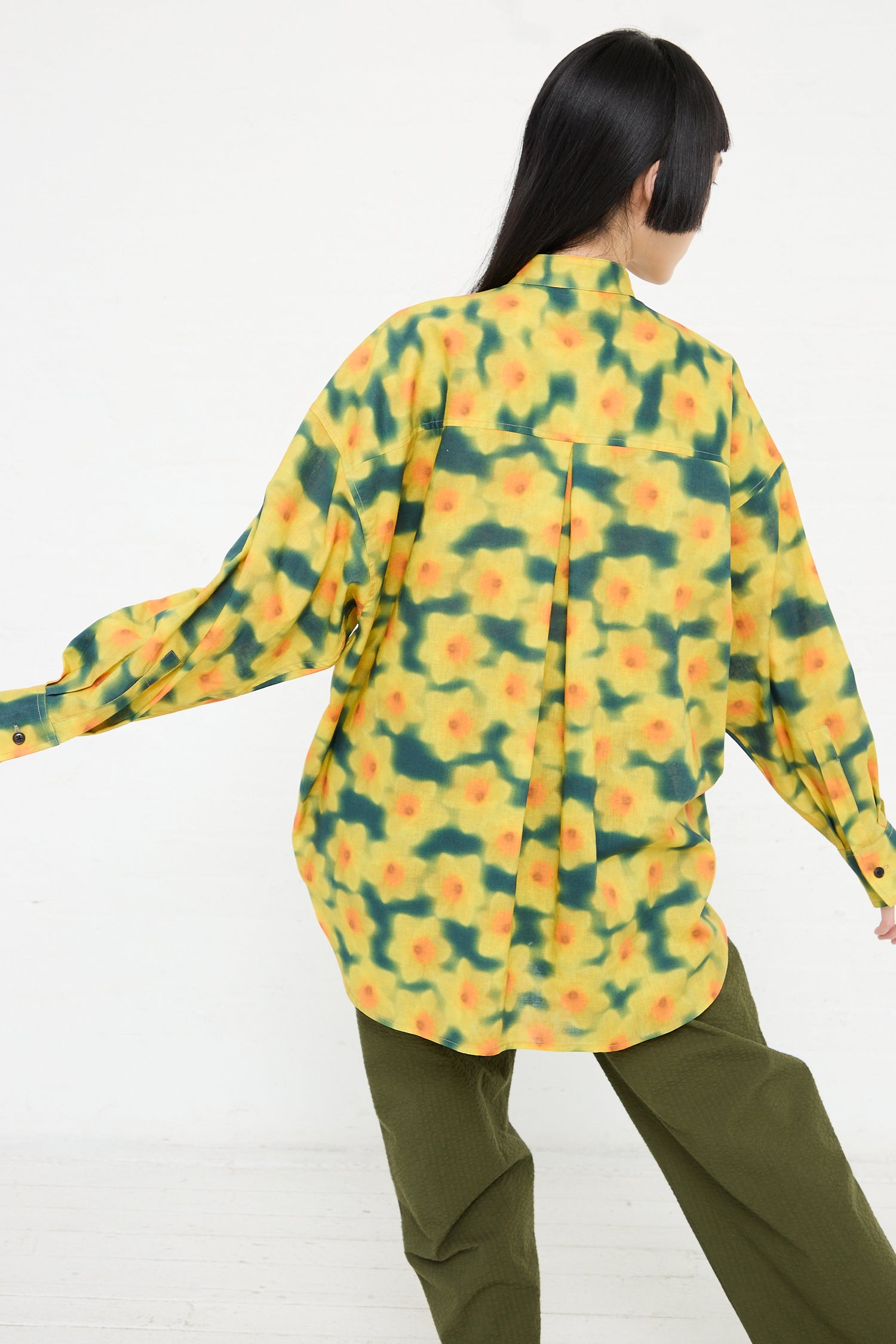Woman wearing a KasMaria Cotton Linen Large Front Pocket Shirt in Daffodil Print in yellow and green, seen from behind.