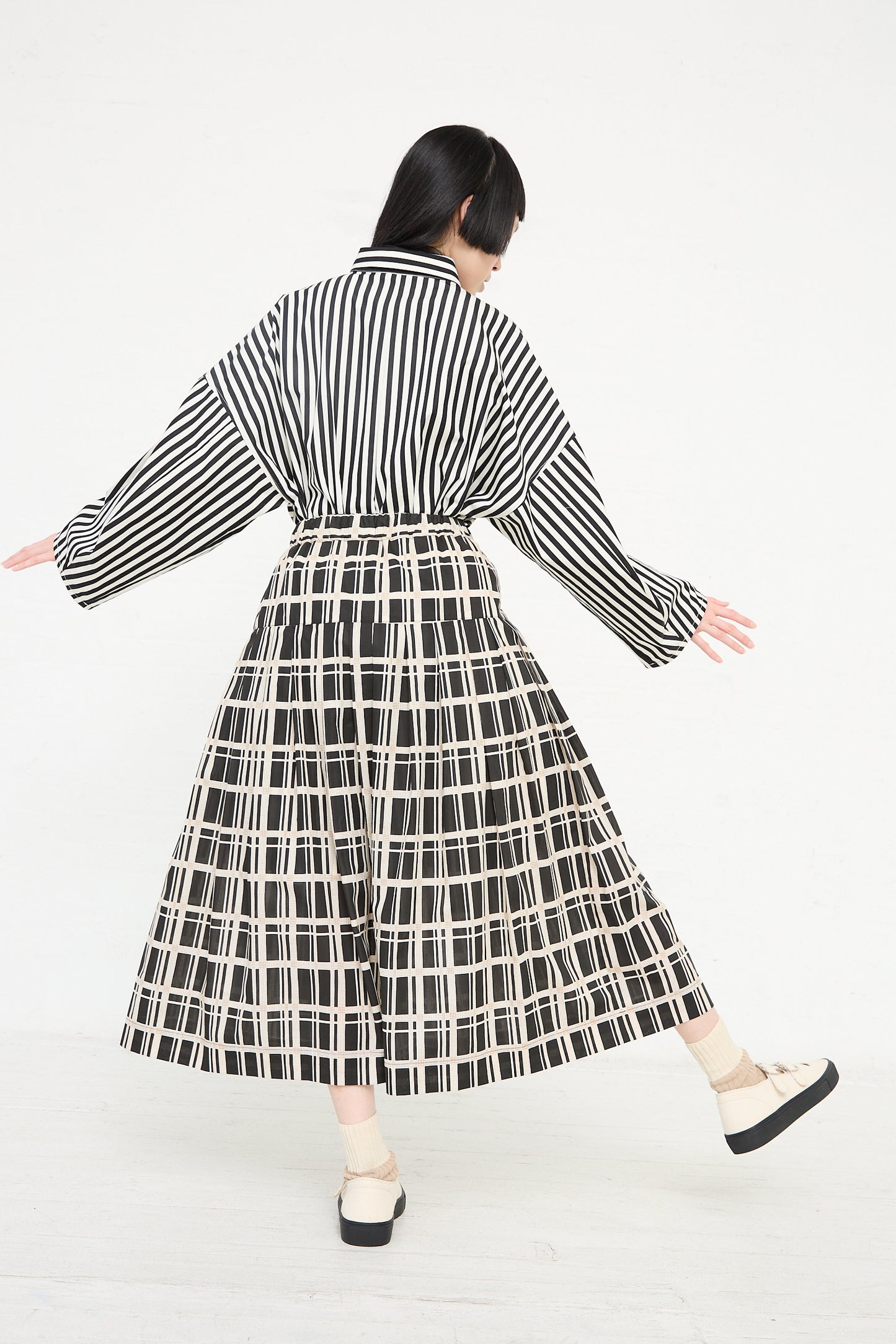 Woman in KasMaria's Cotton Pleated Long Skirt in Grid Print outfit walking away from the camera.