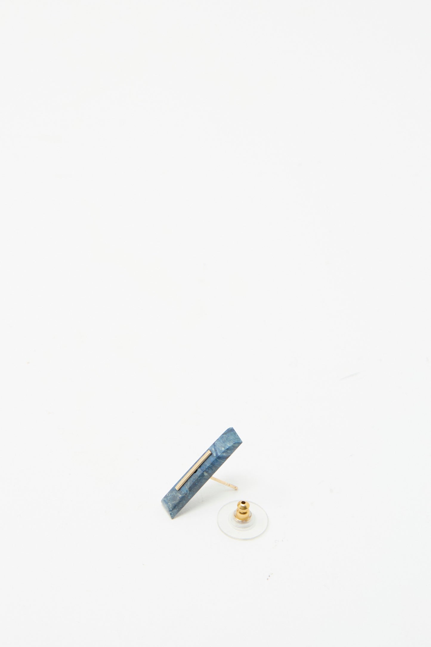 The Kathleen Whitaker 14K Yellow Gold Long Staple Stud 5mm in Lapis showcases a striking rectangular Lapis stone with a clear backing, resting on a white surface.