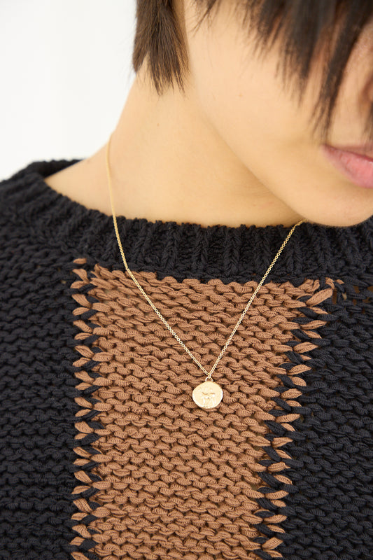 A woman wearing a black sweater with a gold necklace featuring Kathryn Bentley's Stag Coin Pendant.