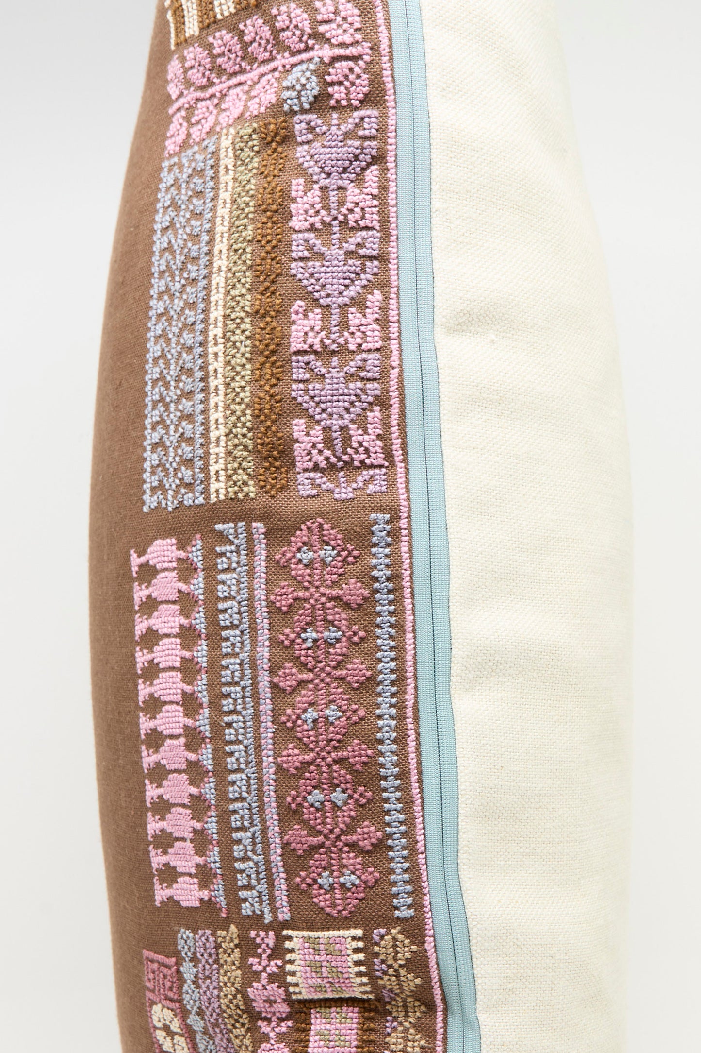 The Imm Bushra Hand Embroidered Pillow in Chocolate by Kissweh features intricate pink, purple, and brown geometric designs on one side, plain off-white fabric on the other, and a plush down feather insert for comfort.