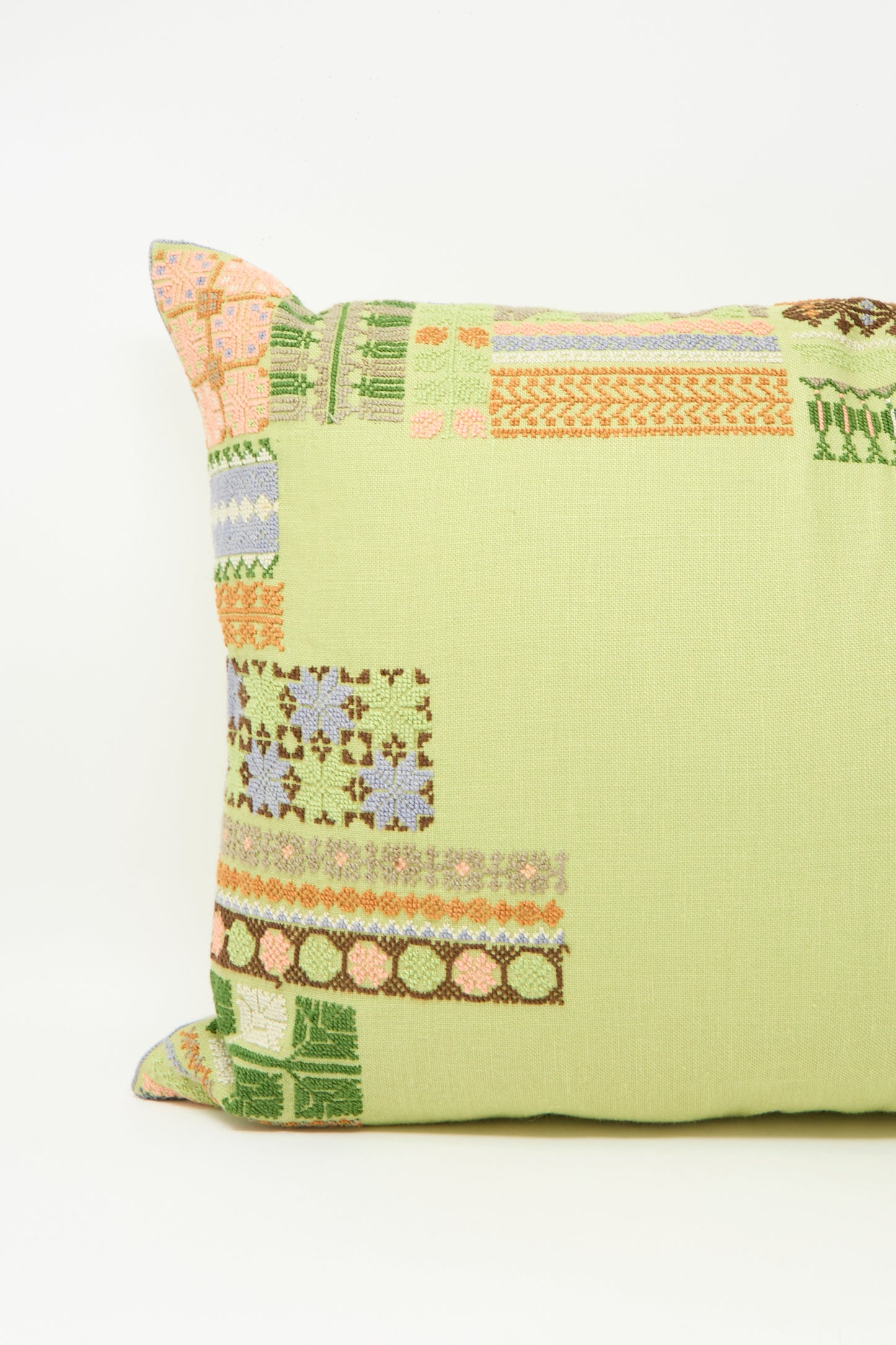 The Imm Bushra Hand Embroidered Pillow in Olive by Kissweh features multicolored geometric embroidery on light green Belgian linen, with a plush down feather insert for comfort.