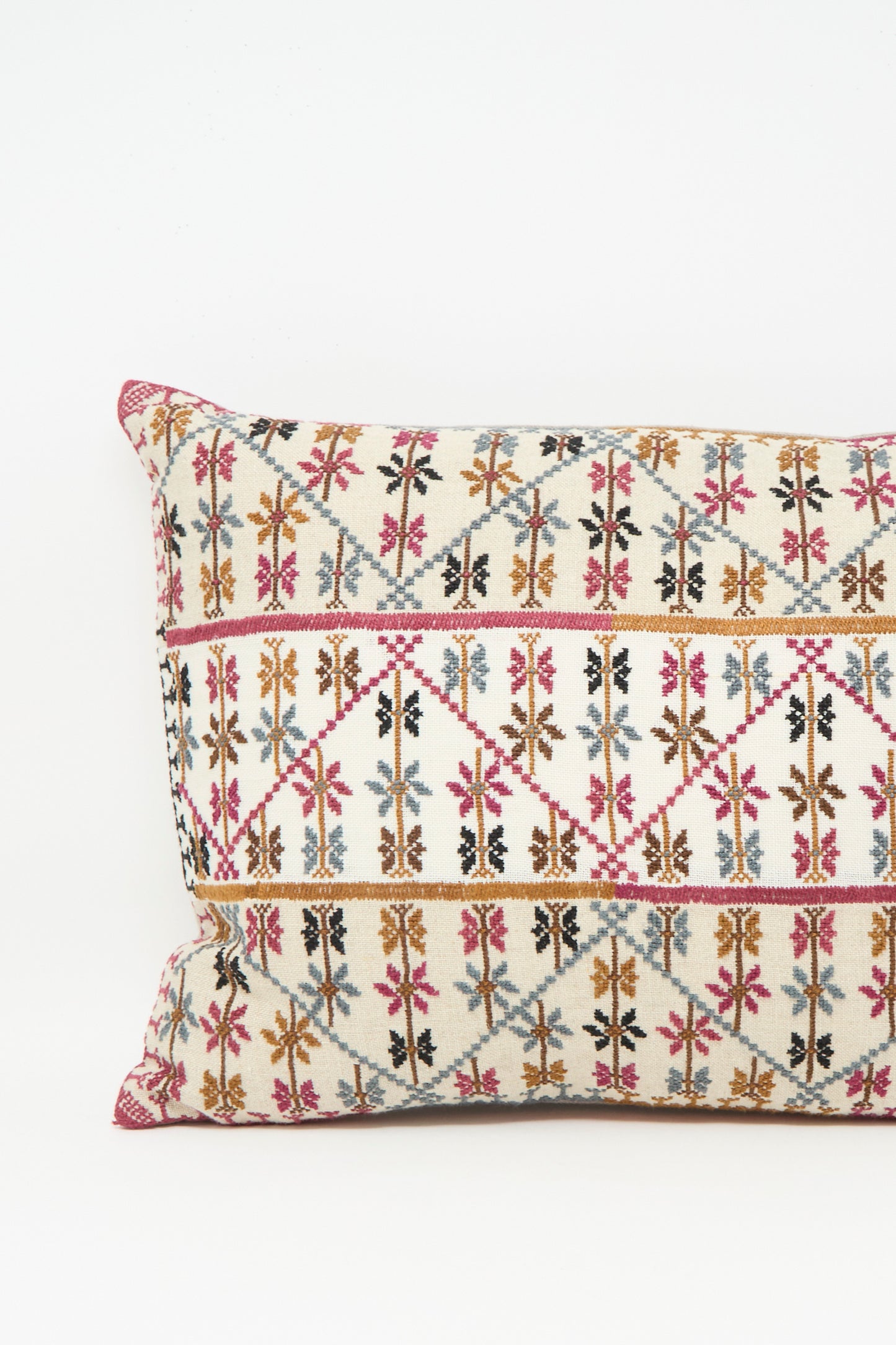 The Kissweh Imm Omar Hand Embroidered Pillow in Beige and Chocolate features intricate geometric and floral designs in pink, brown, black, and blue on a cream background. Includes plush down feather insert; shown on a plain white surface.