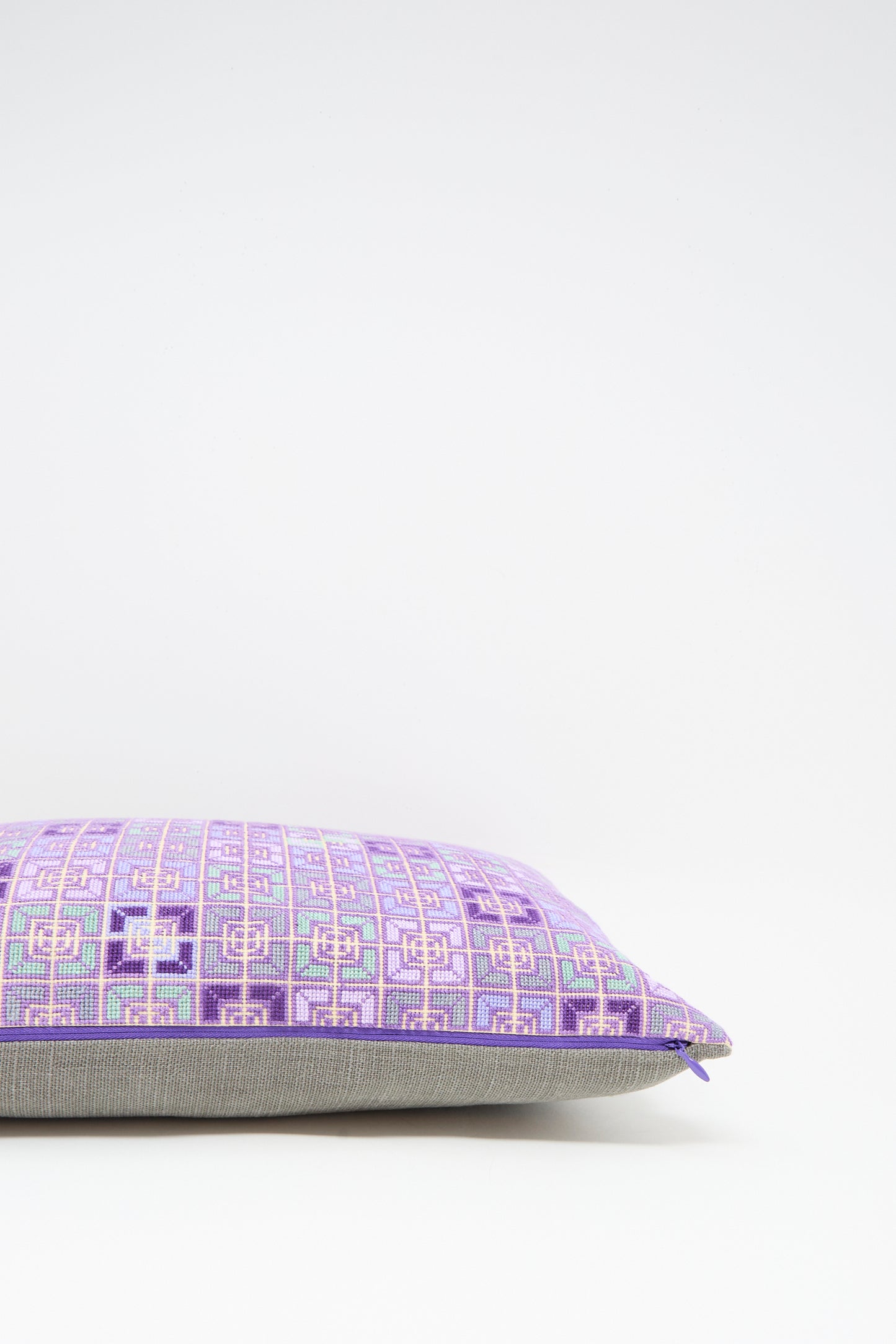 The Kissweh Rana Hand Embroidered Pillow in Lilac and Purple II features a geometric pattern over beige Belgian linen, shown against a white background.