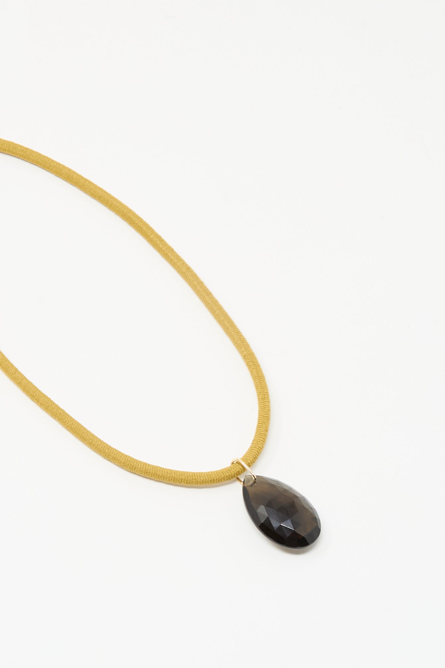 The Drop Cord in Tan and Smoky Quartz by Laoli features a handmade teardrop-shaped smoky quartz pendant on a tan cord, displayed against a white background.