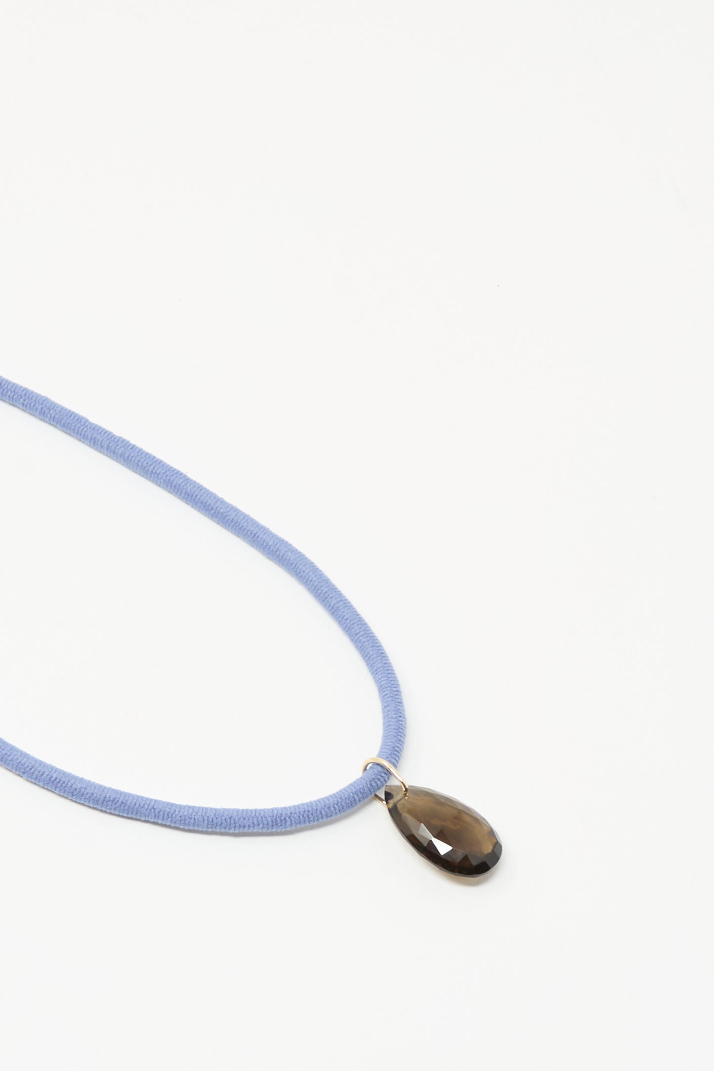 The Petite Drop Cord in Blue and Smoky Quartz by Laoli is a handmade necklace featuring a blue cord and a teardrop smoky quartz pendant, crafted in Paris, shown against a white background.