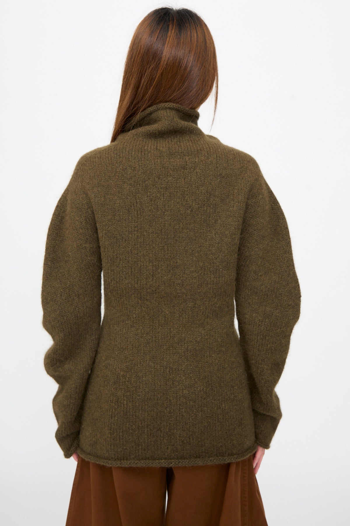 Back view of a person wearing an olive Bottle Turtleneck in Olive baby alpaca sweater.
