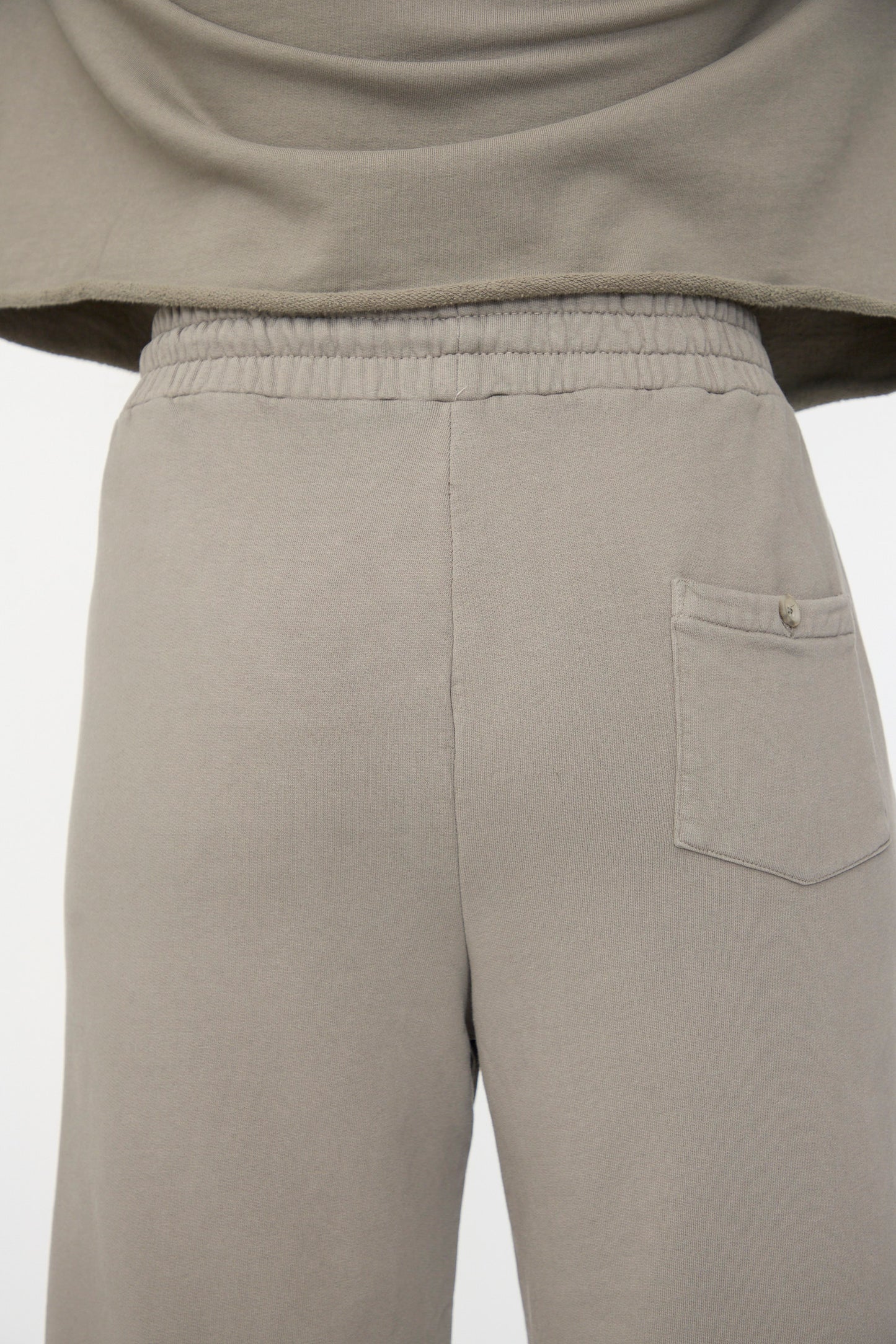 Close-up of the back of a person wearing Lauren Manoogian's Fleece Pants in Fatigue, featuring a relaxed fit, elastic waistband, and a single buttoned pocket on the right side.