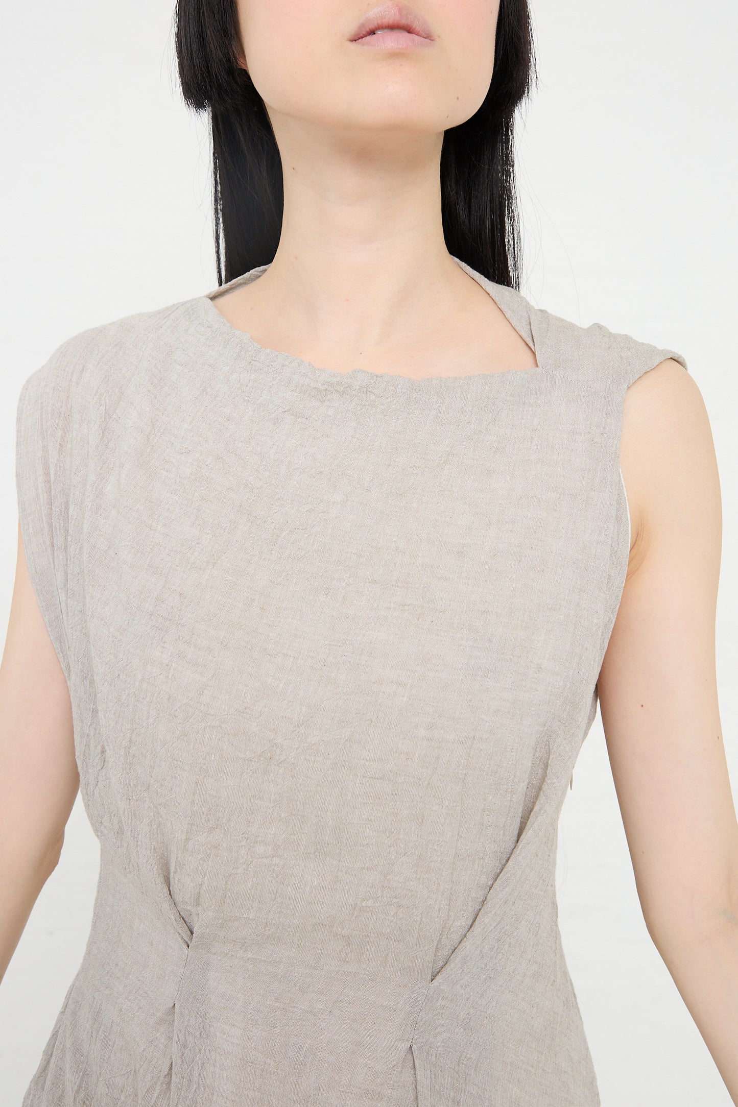 Close-up of a woman in a Lauren Manoogian Gauze Twist Dress in Ash, focusing on the garment's texture and neckline, with her face partially visible.