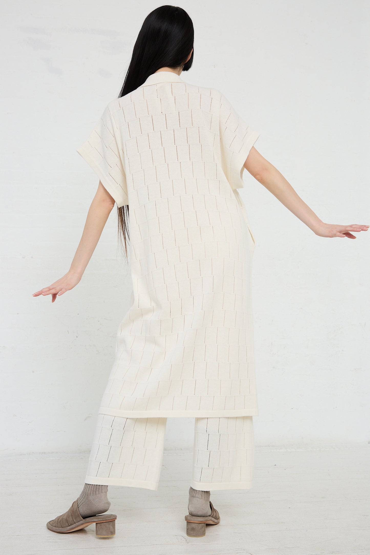 A person facing away from the camera models a Lattice Shirt Dress in Bone by Lauren Manoogian, with trousers and a matching linen blend top.