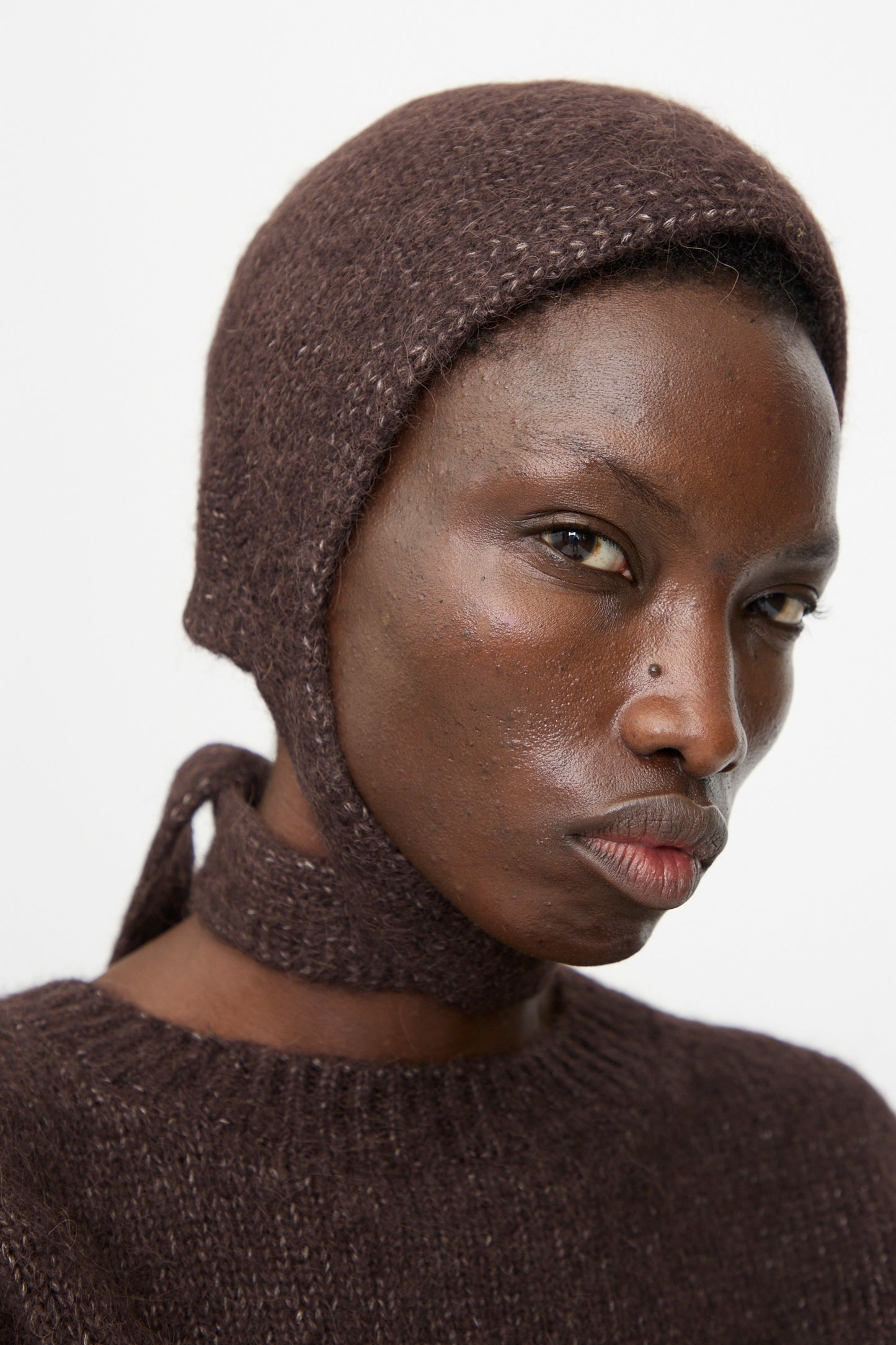 Model wearing the Lauren Manoogian Loft Bonnet in Soil, a fitted bonnet made from a luxurious suri alpaca blend, looking at the camera against a plain white background. Made in Peru.