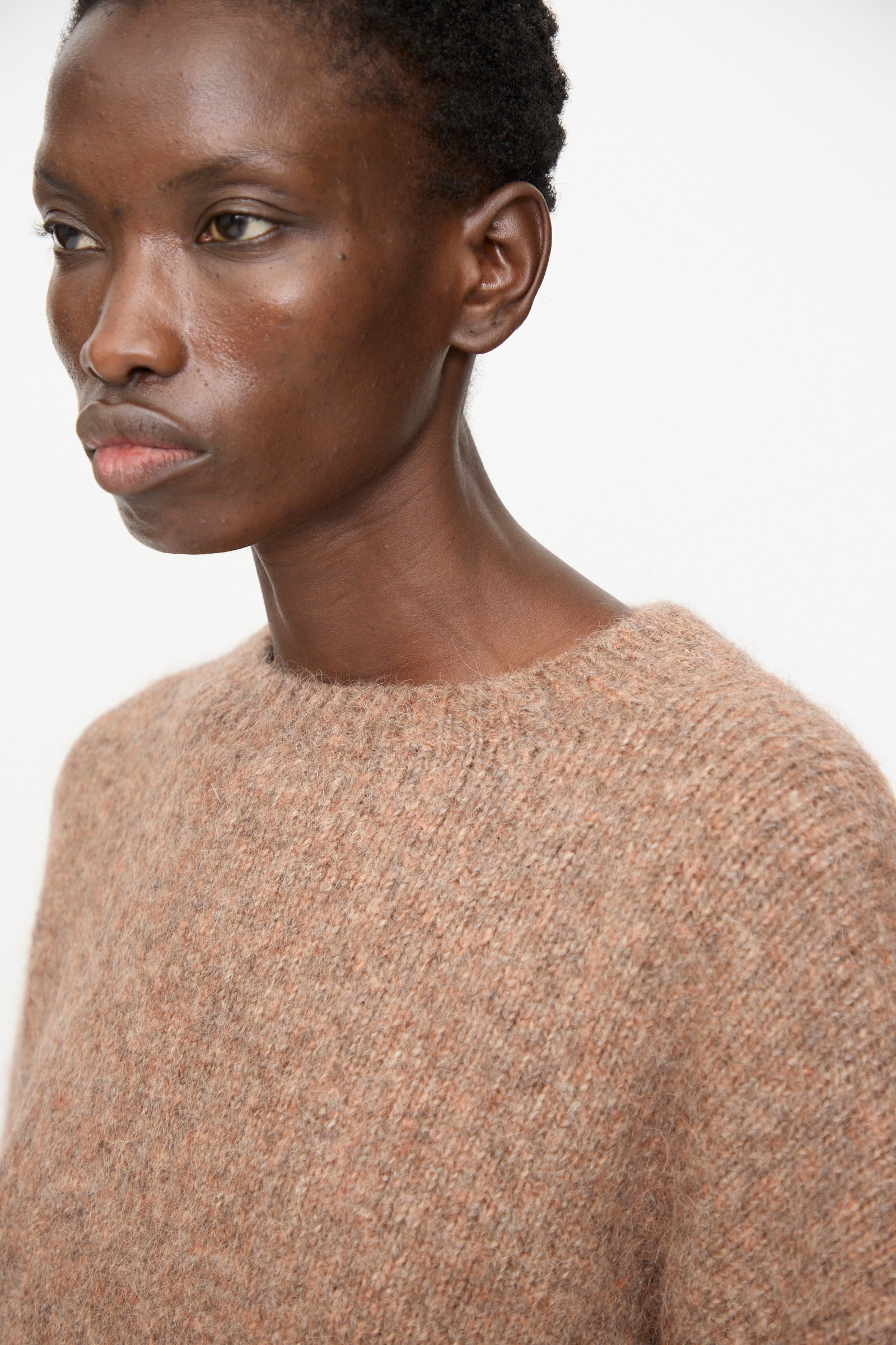 A person wears the Lauren Manoogian Loft Crewneck in Spice, standing against a plain white background and looking slightly to the left.