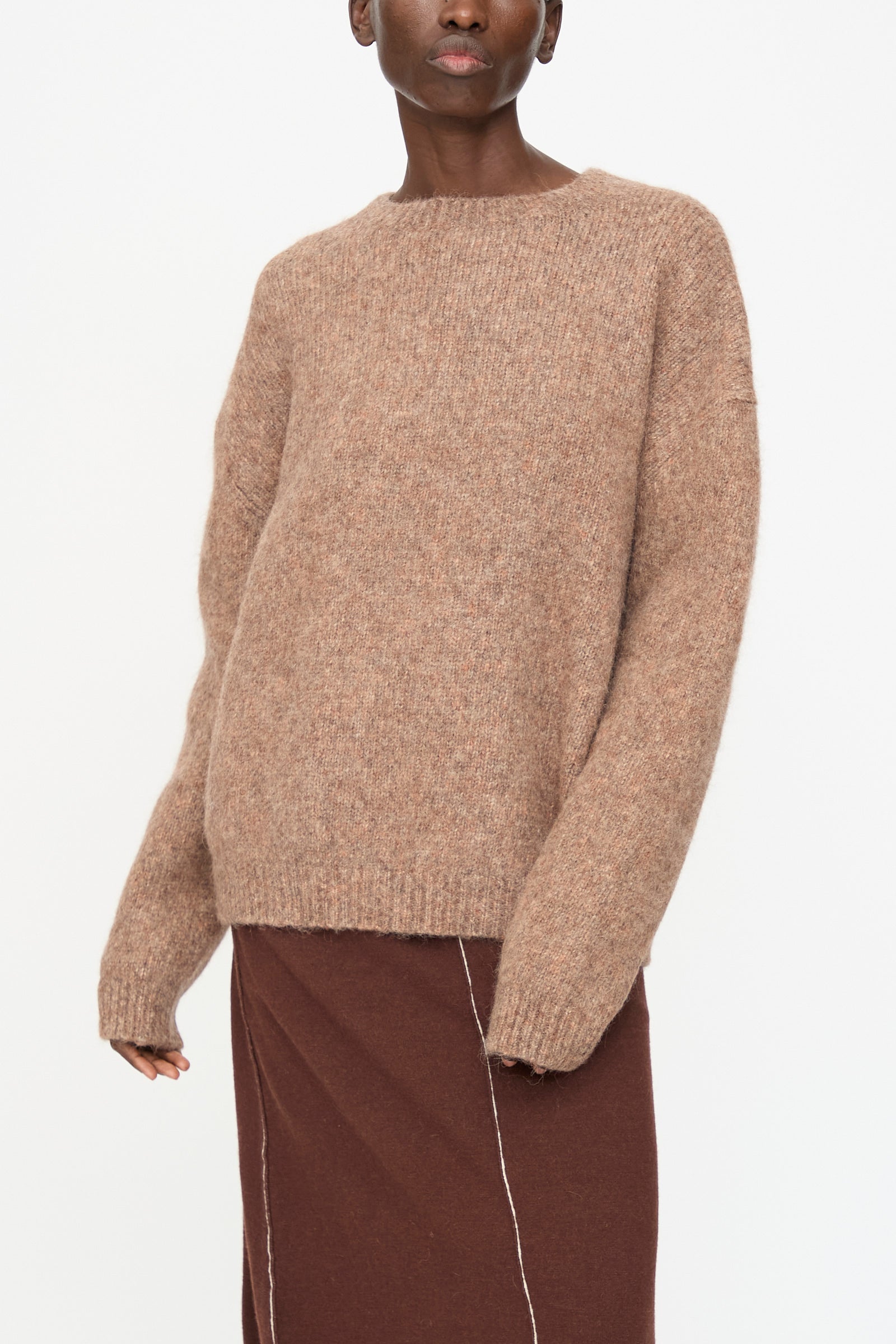 A person wears the Lauren Manoogian Loft Crewneck in Spice with a brown skirt, standing against a plain white background.