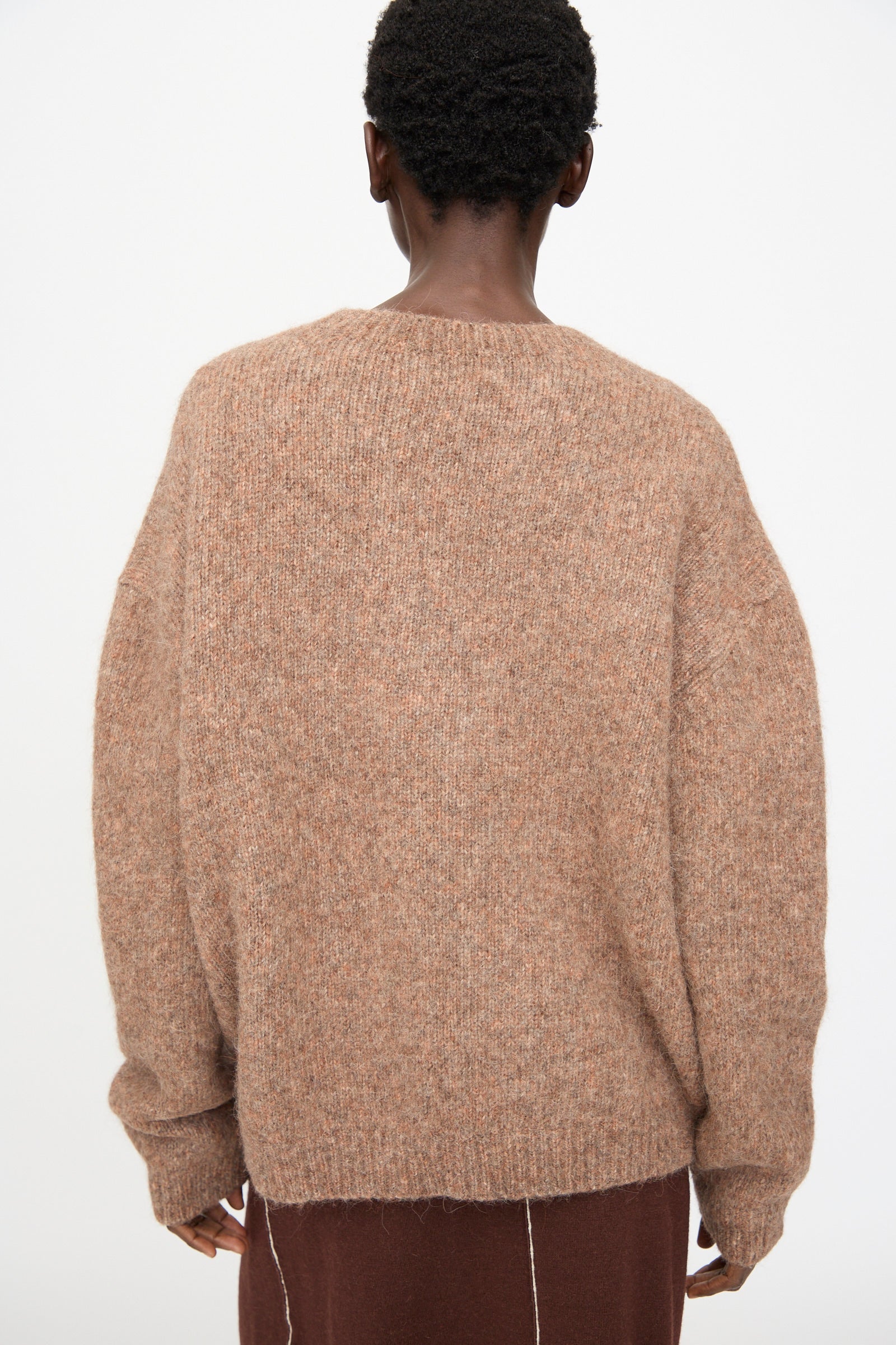 A person stands with their back to the camera, wearing the Lauren Manoogian Loft Crewneck in Spice and a brown skirt against a plain background.