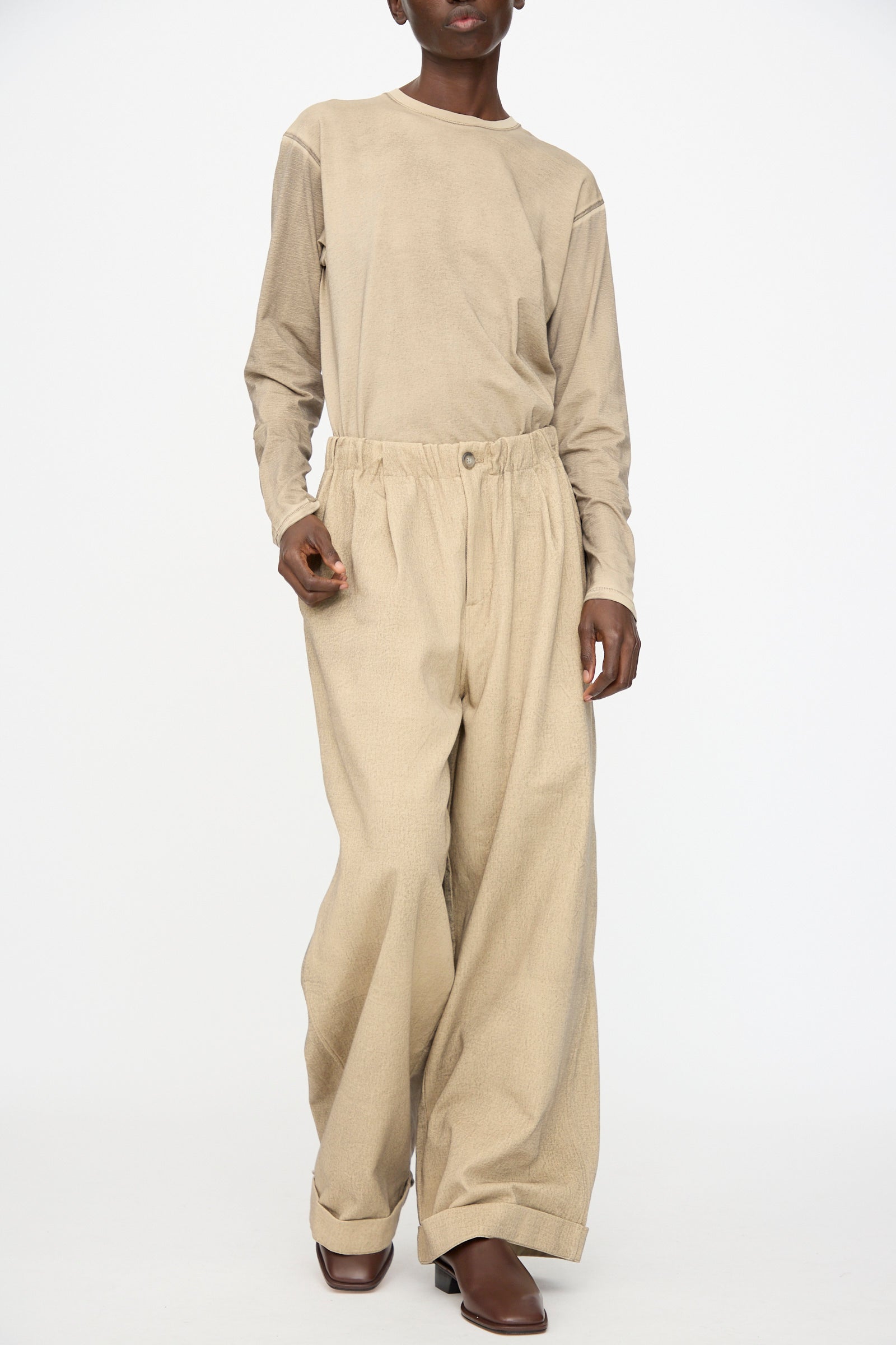 Model wearing Lauren Manoogian's Painted Trouser in Antique paired with a beige long-sleeve shirt and brown boots, standing against a plain white background.