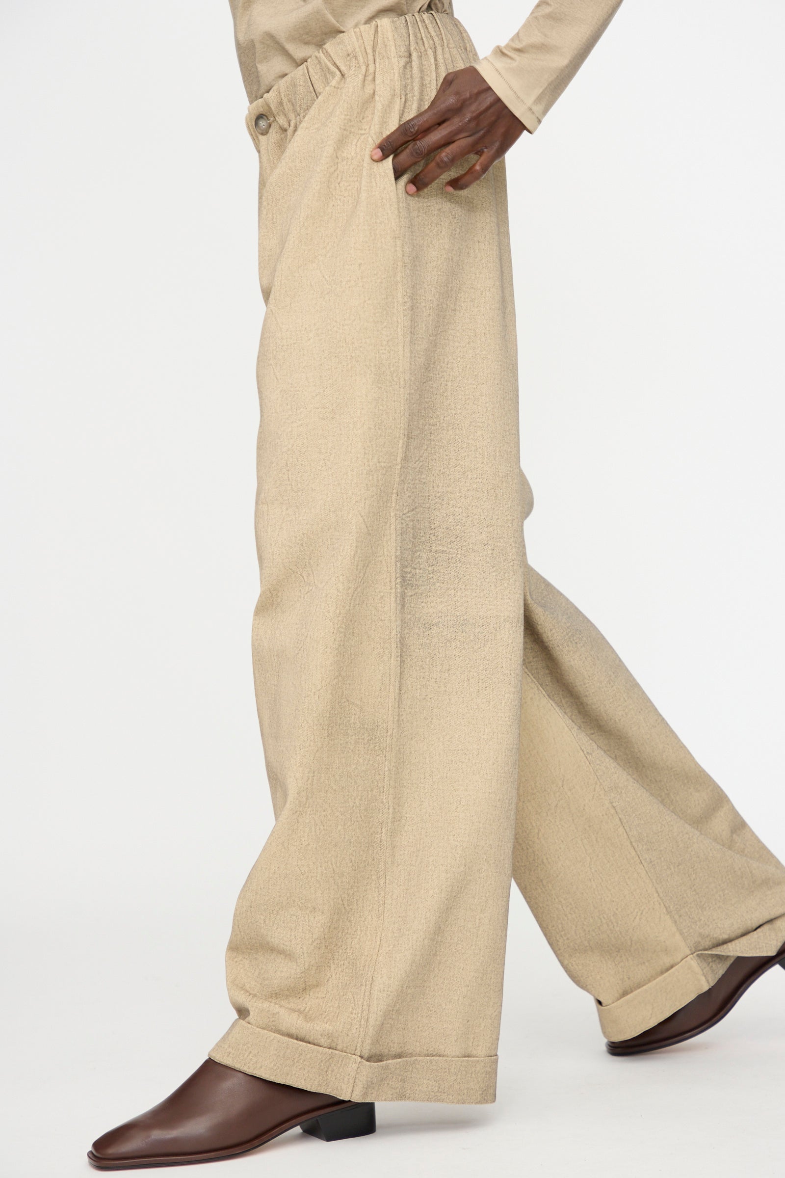 Model wears Lauren Manoogian Painted Trouser in Antique, an oversized fit wide leg beige cotton pant, paired with brown ankle boots—shown from the waist down against a plain white background.
